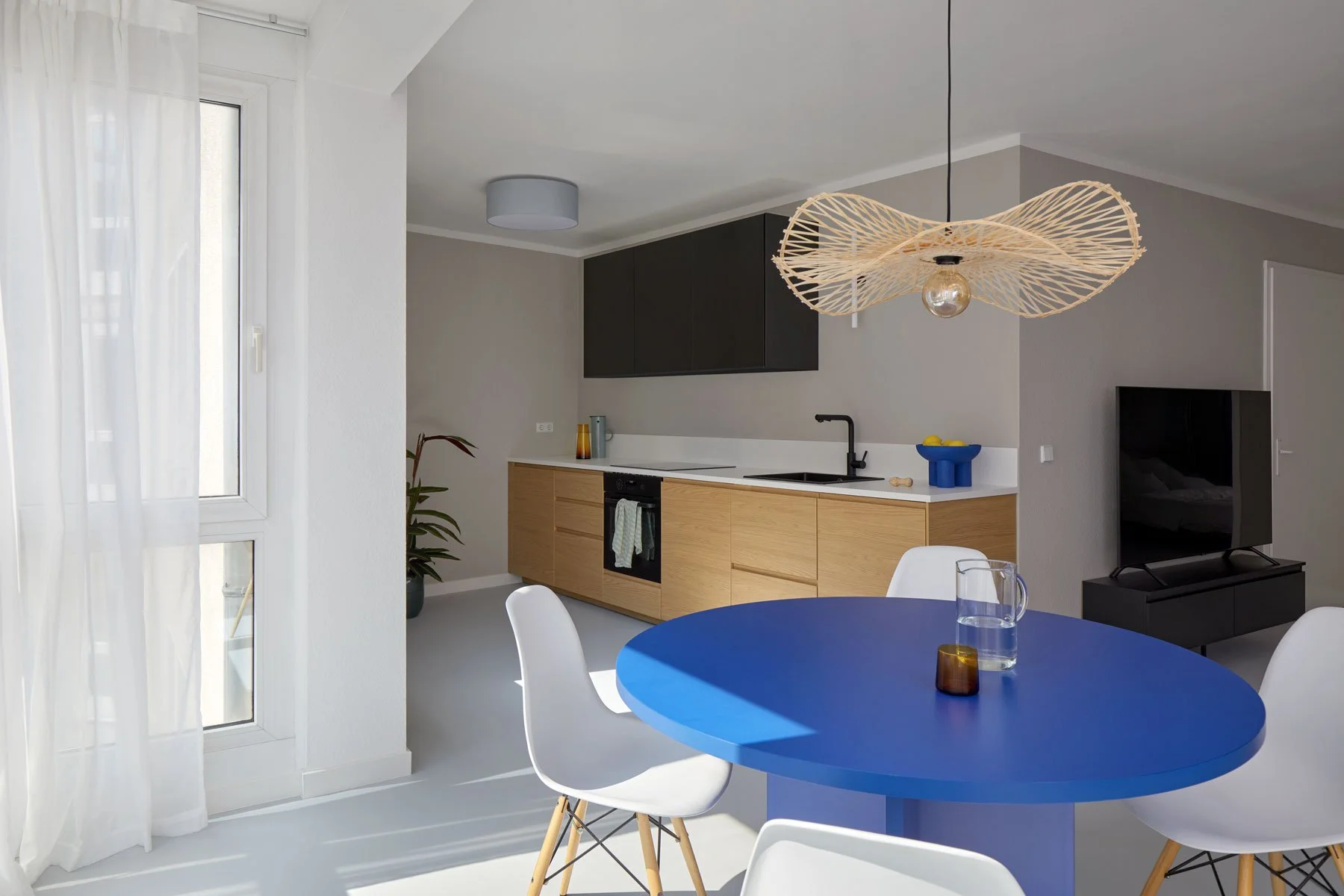 Open kitchen and dining area with blue round table and oak cabinetry, apartment in Berlin Mitte, interior design, Innenausbau, Ausstattung and styling by Steffi Bühlmaier, photography by Tobias Bärmann, 2024
