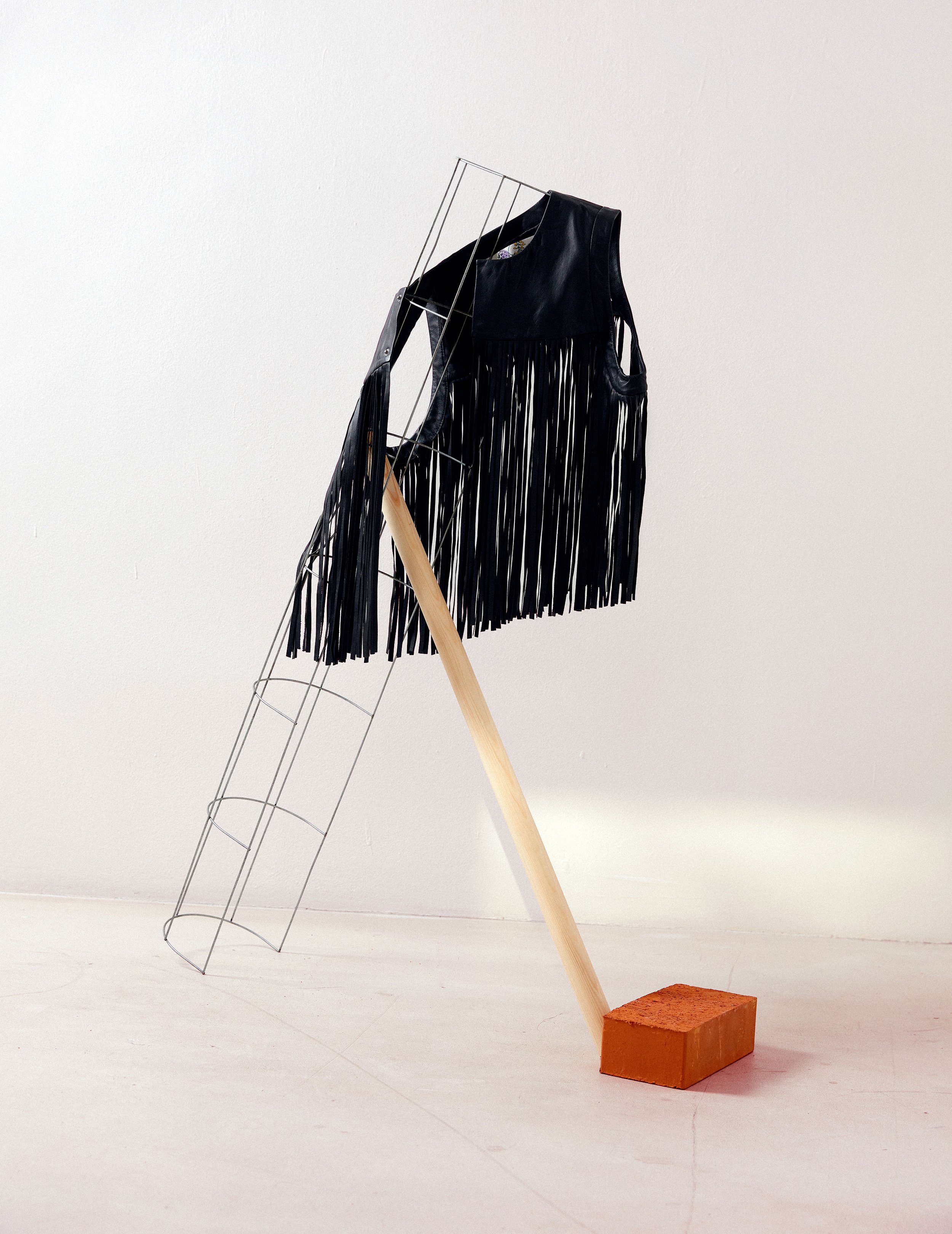 Still life editorial featuring black fringe leather vest on metal structure with wooden support, art direction and styling by Steffi Bühlmaier, photography by Jessica Grossmann for Heyday Magazine, 2022