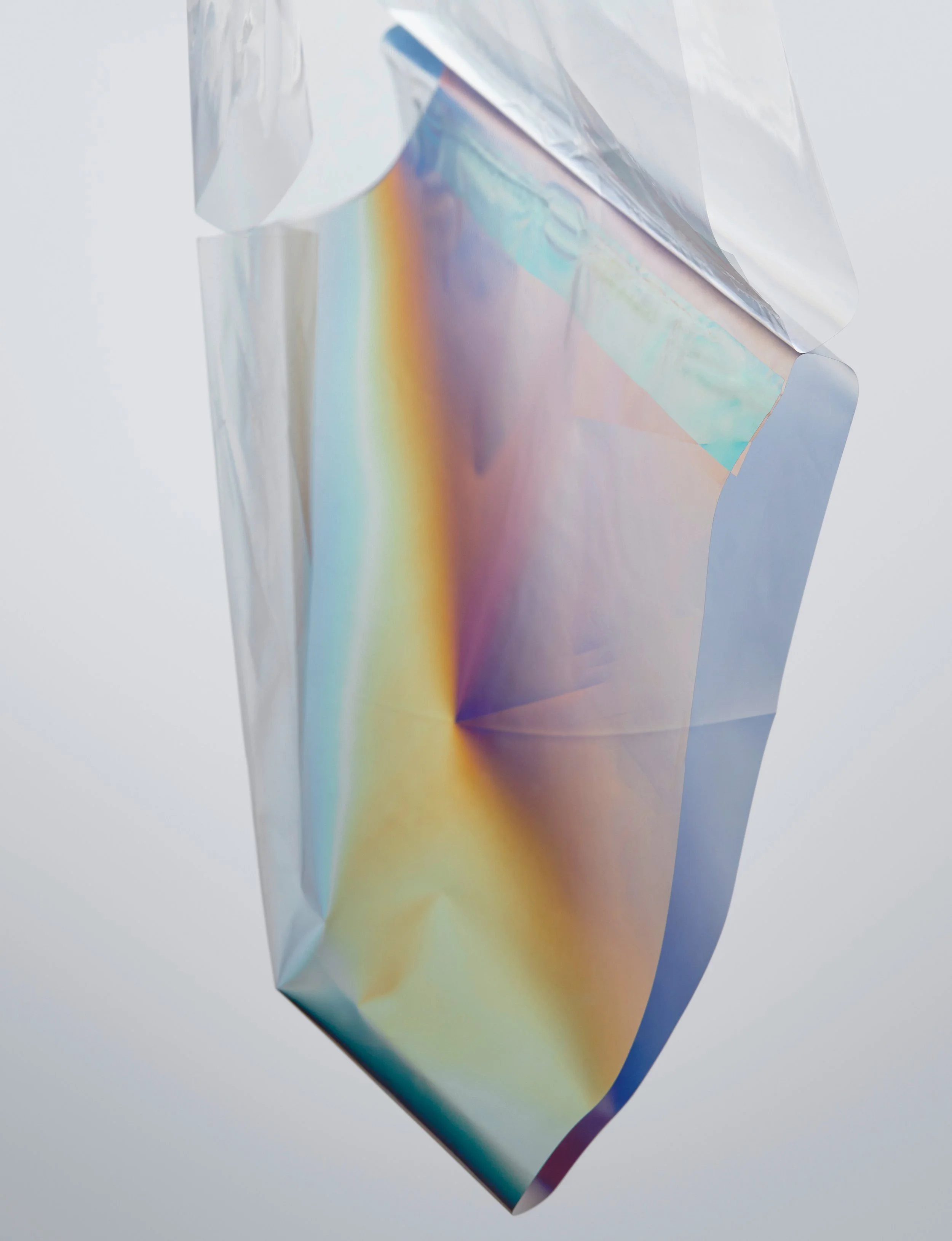 Close-up of iridescent packaging film splitting light into rainbow spectrum through controlled lighting setup, props styling by Steffi Bühlmaier, photography by Tobias Bärmann, postproduction by Studio Wolfram, published in Slanted 38, 2018
