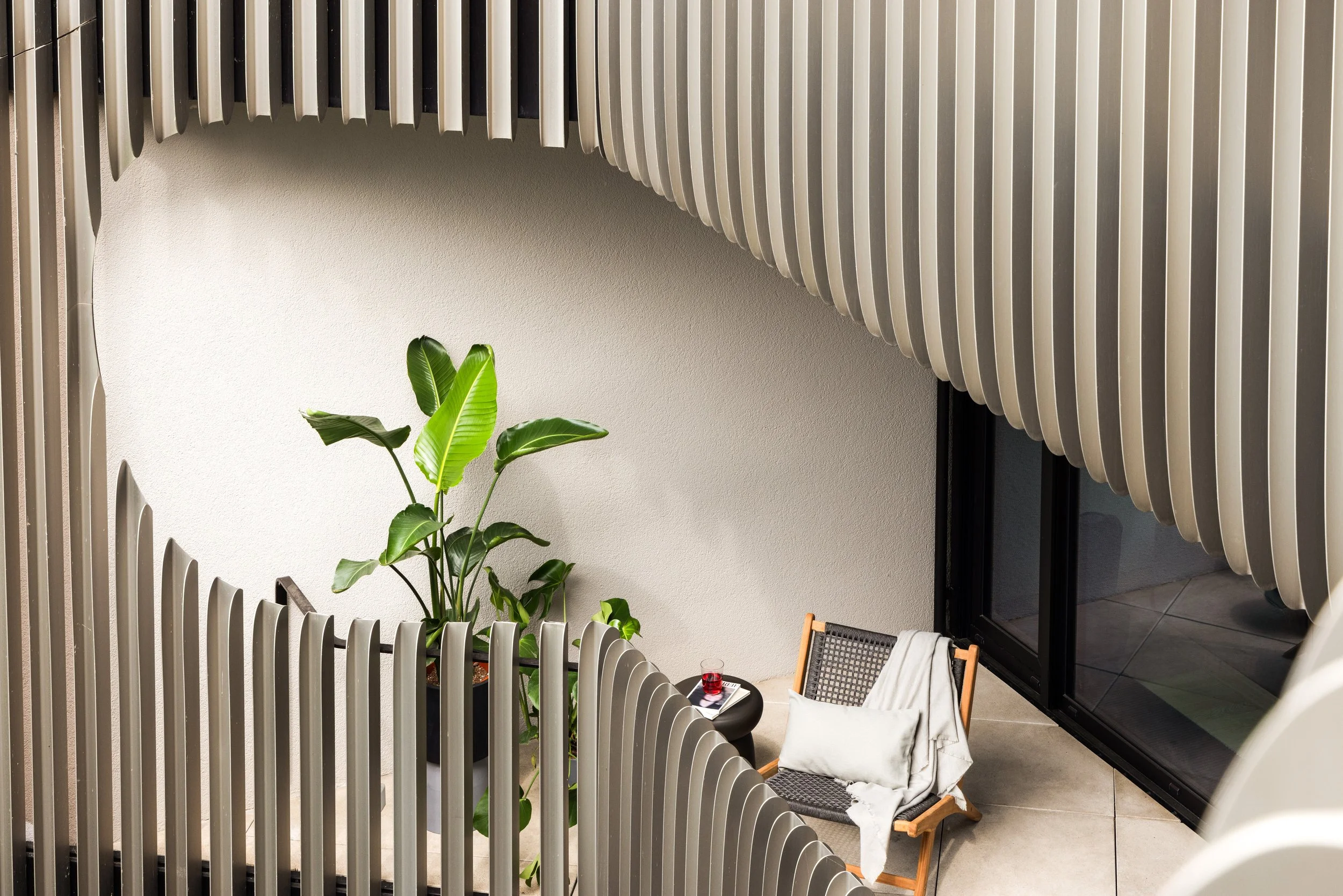 Apartment balcony in Berlin Mitte with sculptural railing, lounge chair and plants, home staging and interior styling by Steffi Bühlmaier, photography by Jordana Schramm, 2025