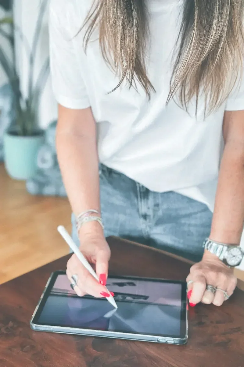 Frau benutzt einen digitalen Stift auf einem Tablet-Computer auf einem Tisch