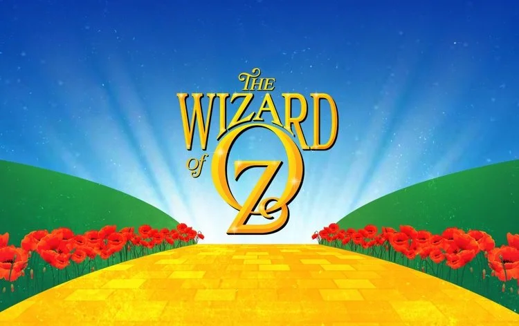 Colorful animated background with a yellow brick road leading to the logo of 'The Wizard of Oz', surrounded by red poppies and green hills under a blue sky with stars.