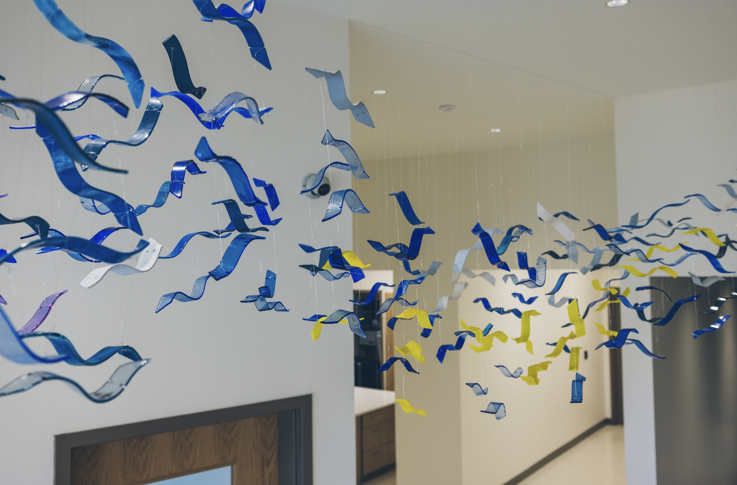 Colorful paper strips in yellow, blue, white, and purple hanging from the ceiling in a hallway.