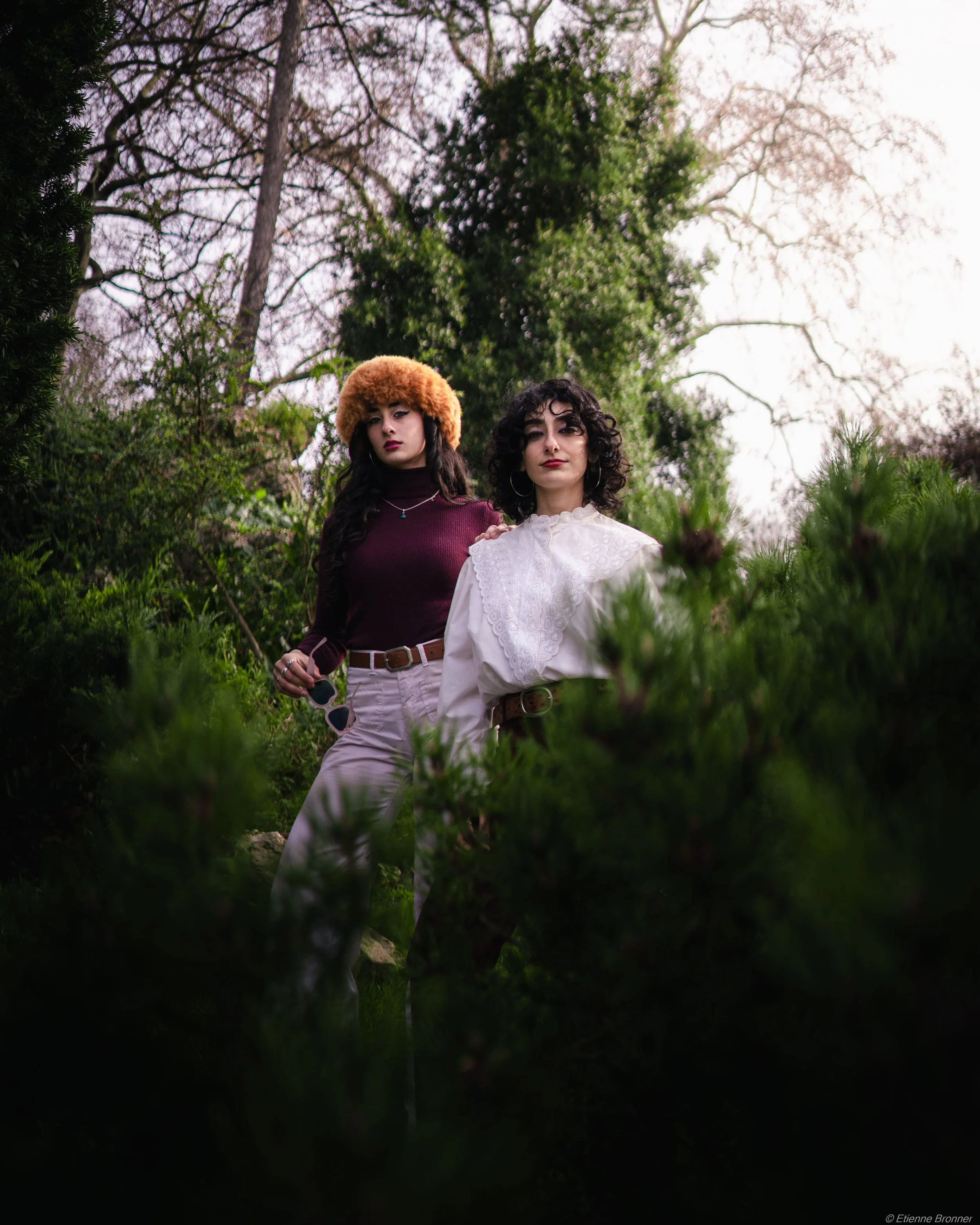 Deux femmes posent dans un coin du parc Monceau, avec des arbres visibles en arrière-plan, sous une lumière naturelle douce.