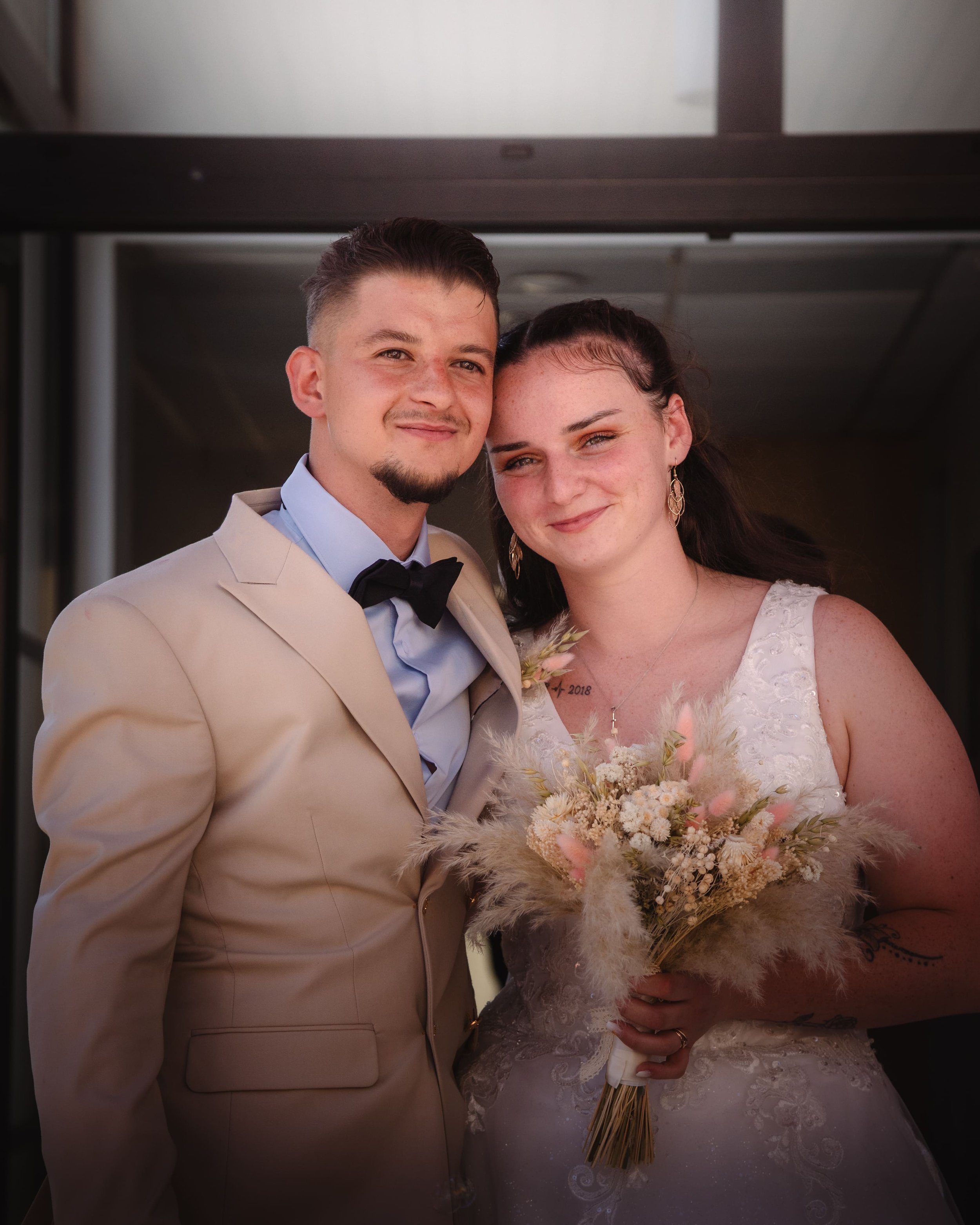 Portrait d'un jeune couple de mariés devant une mairie en Alsace.