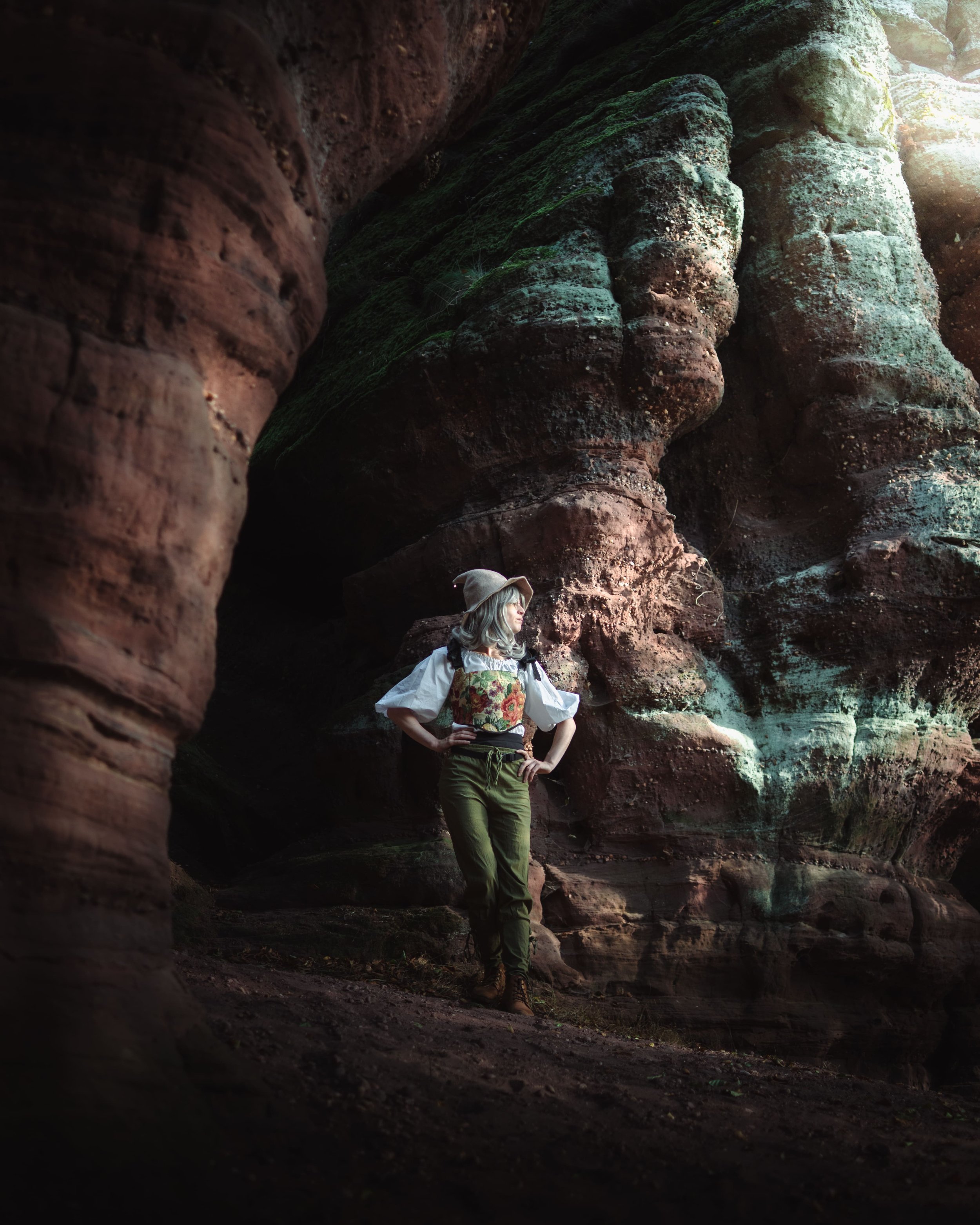 Portrait d'une femme en tenue de lutin des bois, se tenant parmi les roches de la grotte d'amour dans les Vosges du nord.