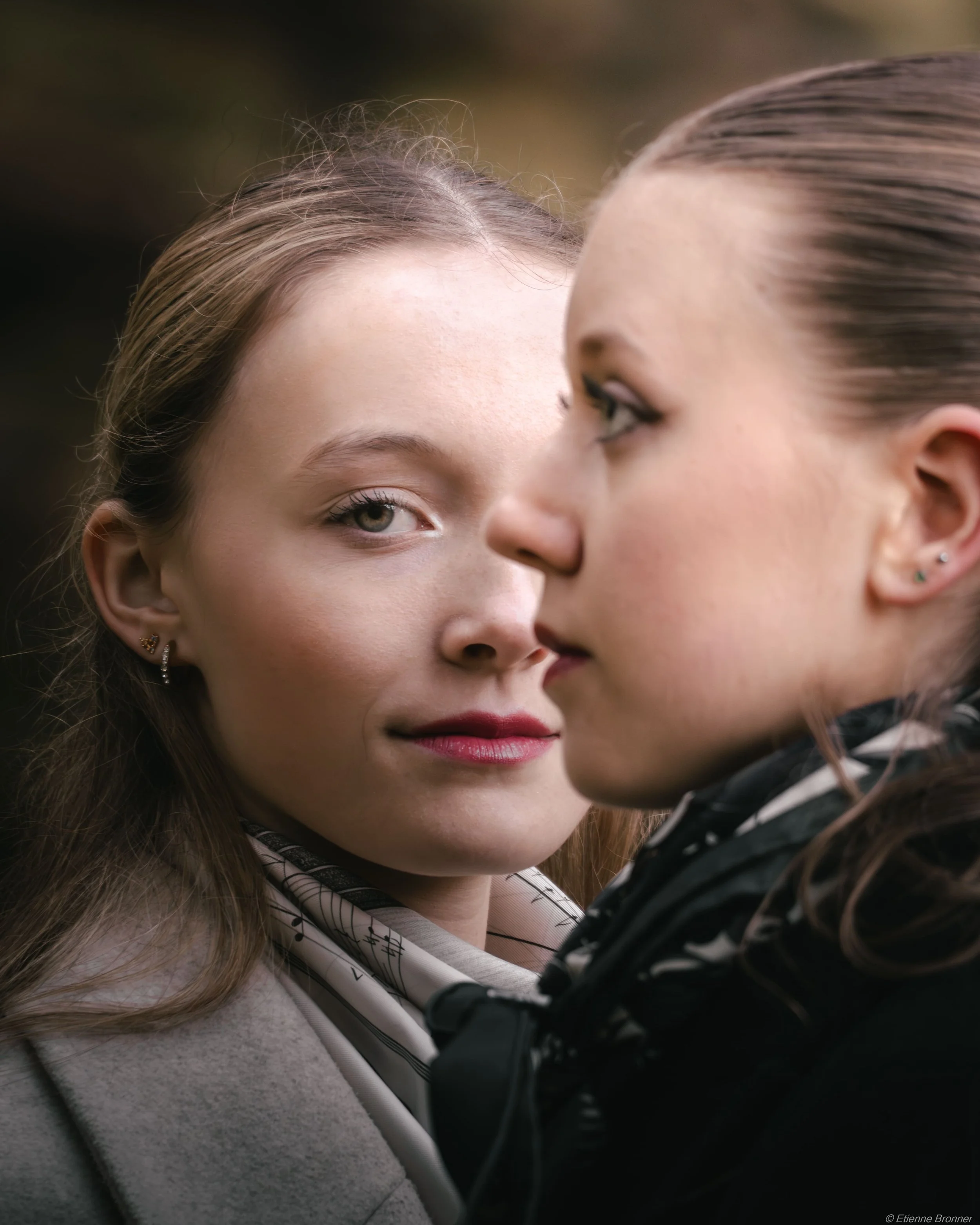 Portrait original de deux jeunes femmes face à face, l'une légèrement en arrière, dans un cadre naturel.