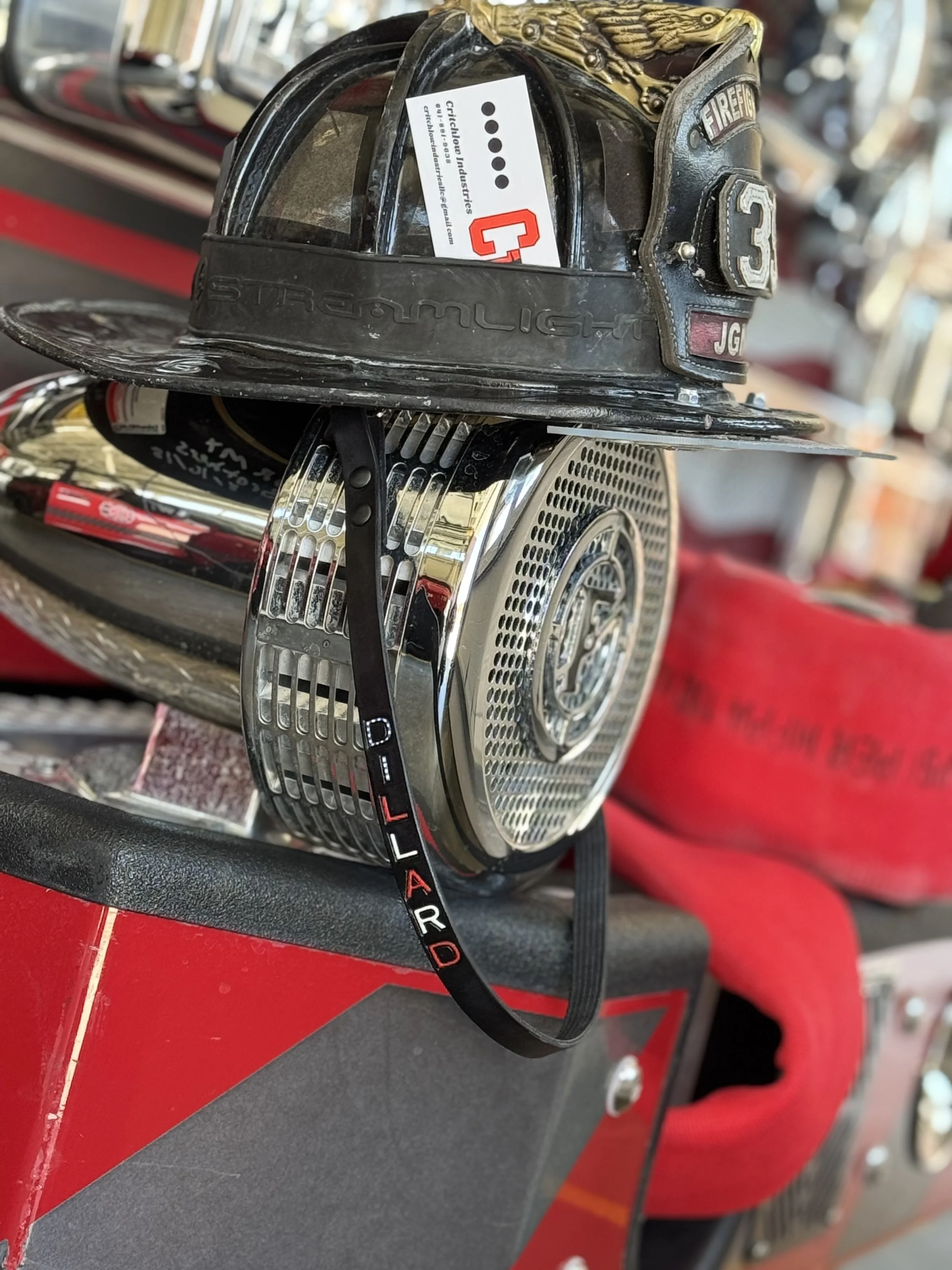 Firefighter helmet, chrome siren, and a red fire truck fire equipment in a garage or fire station.
