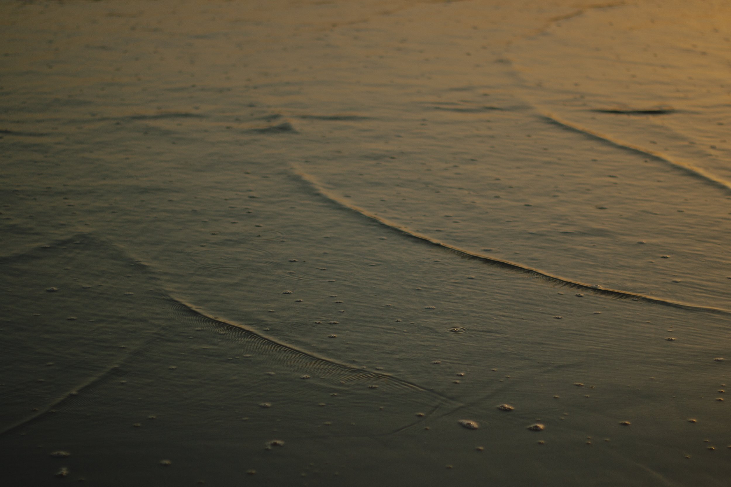 Close-up of a shoreline with gentle waves at sunset.