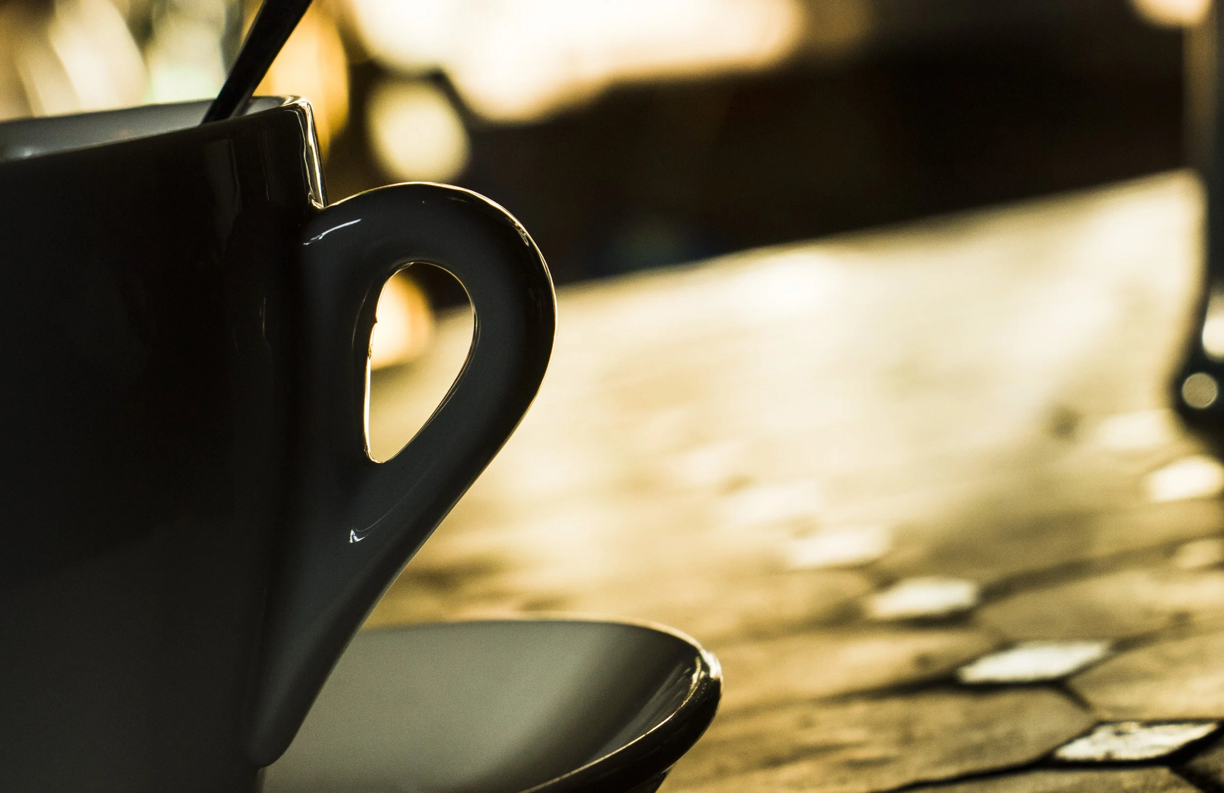 Close-up of a coffee mug on a wooden table, with blurred background and warm lighting.