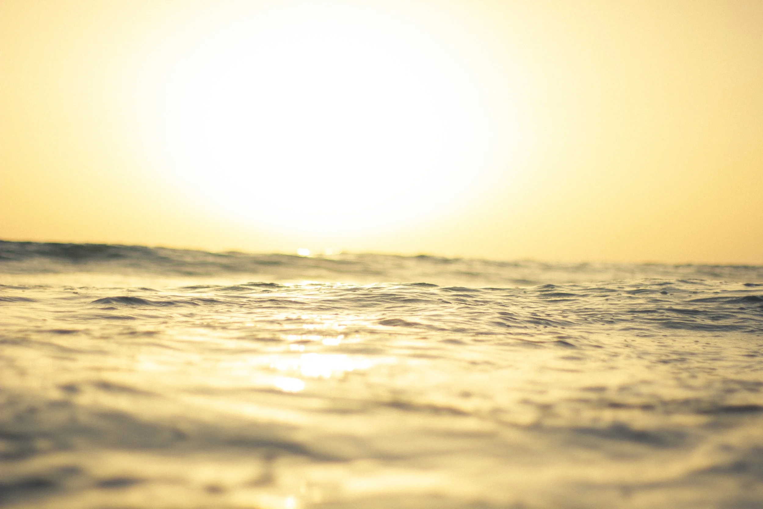 Sunset over the ocean with golden light reflecting on the water.