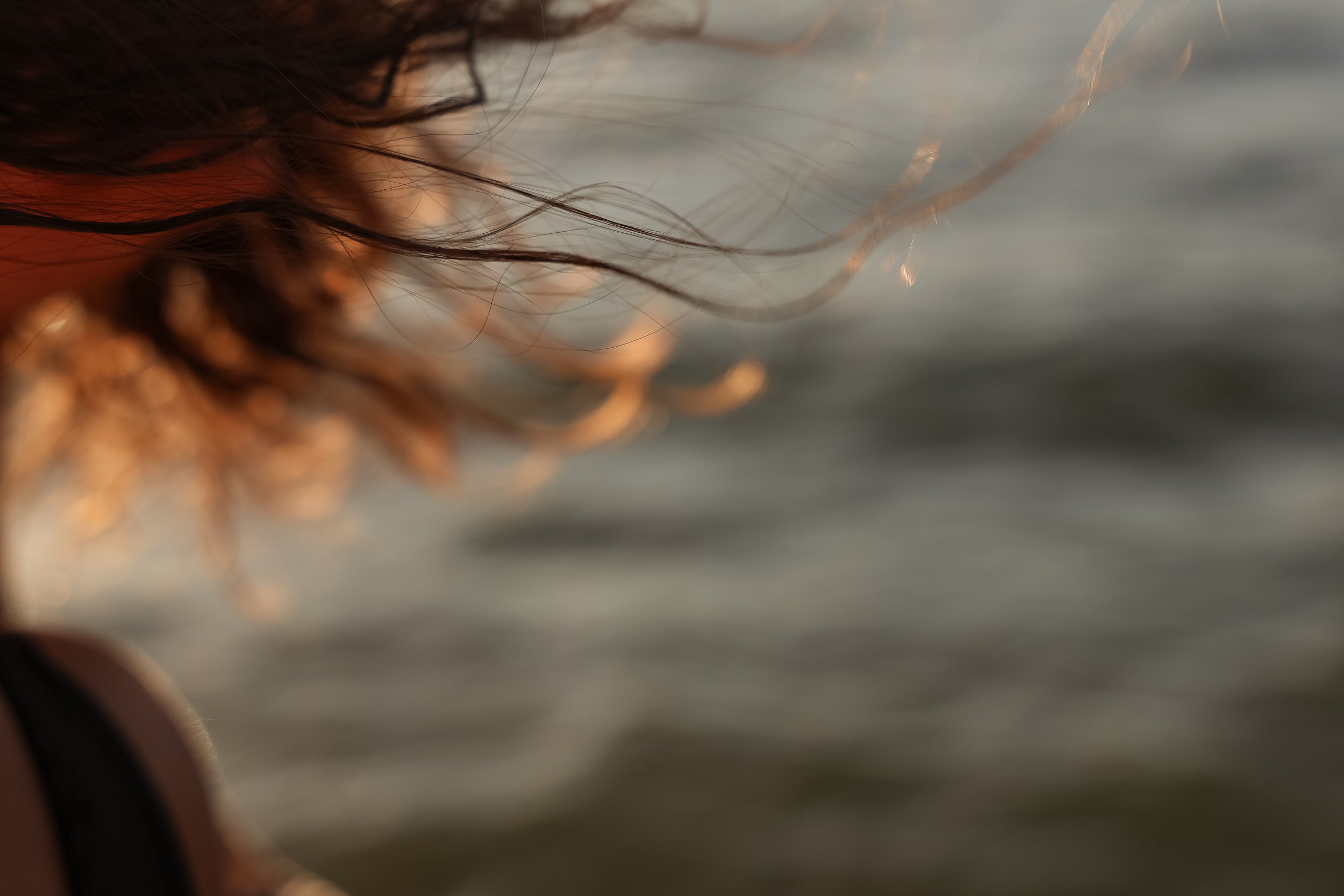 Close-up of a person with wet hair near water, with blurred water in the background.