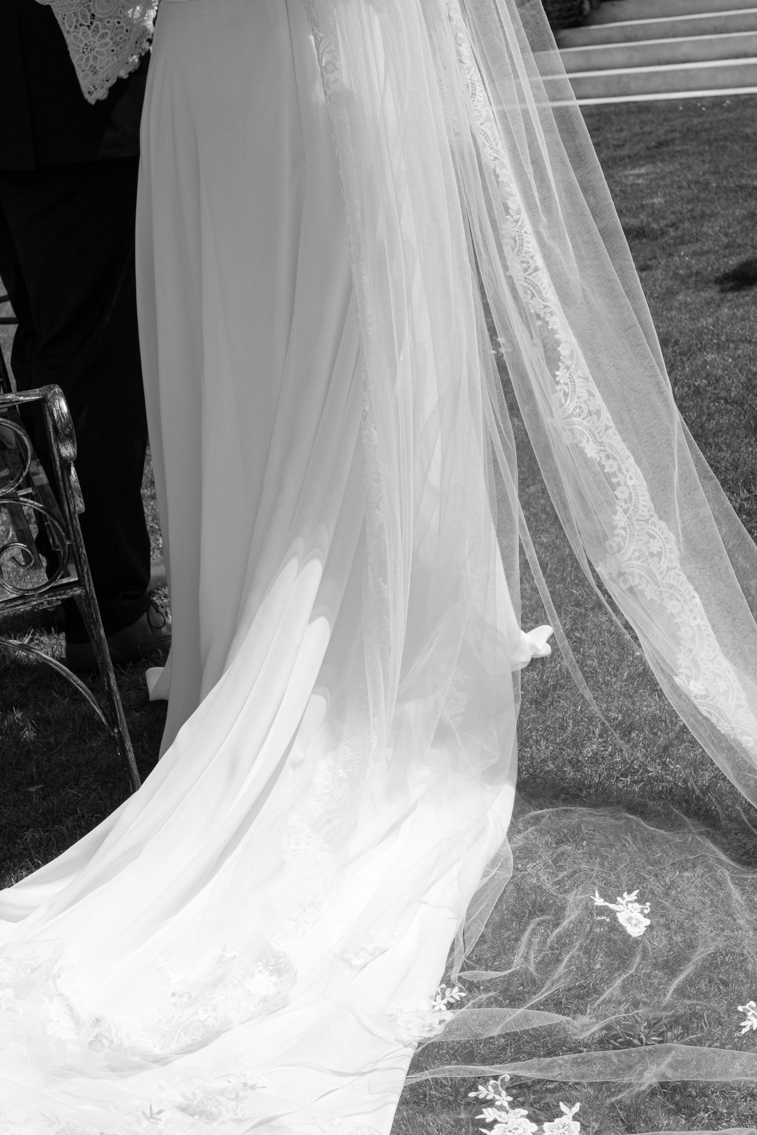 Detailed view of a wedding dress with lace and tulle fabric, on a grassy outdoor setting.