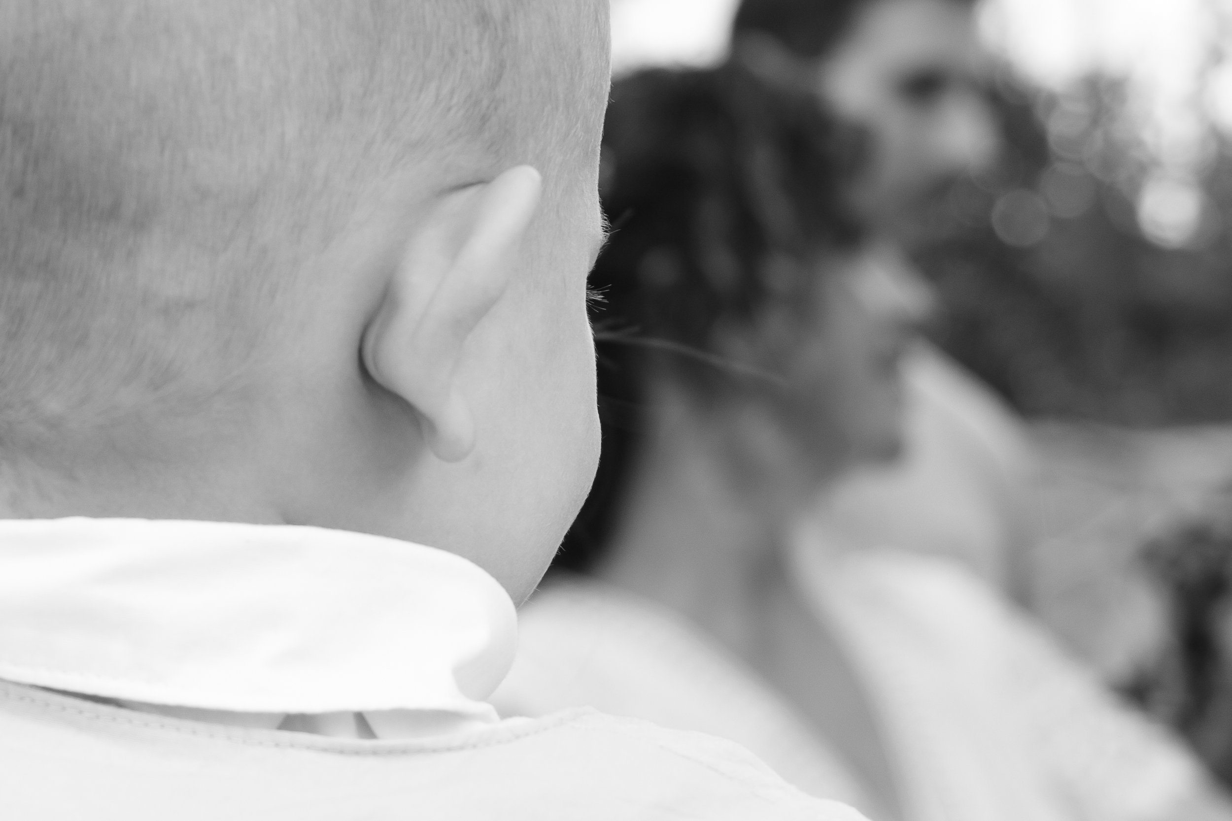 Close-up of a young child's head in black and white, with a blurred woman in the background.