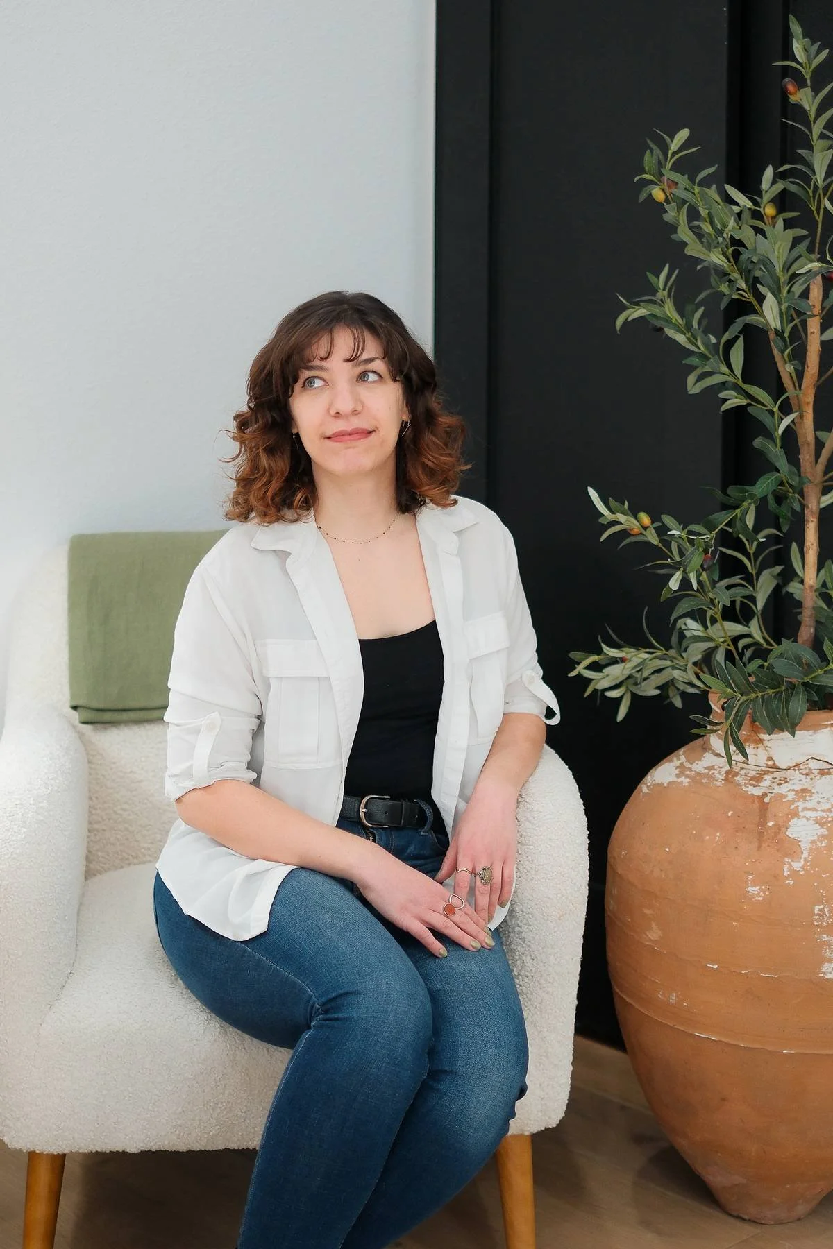 Copywriter Rebecca Brumberg sitting on a chair and gazing off to the side with a soft smile.