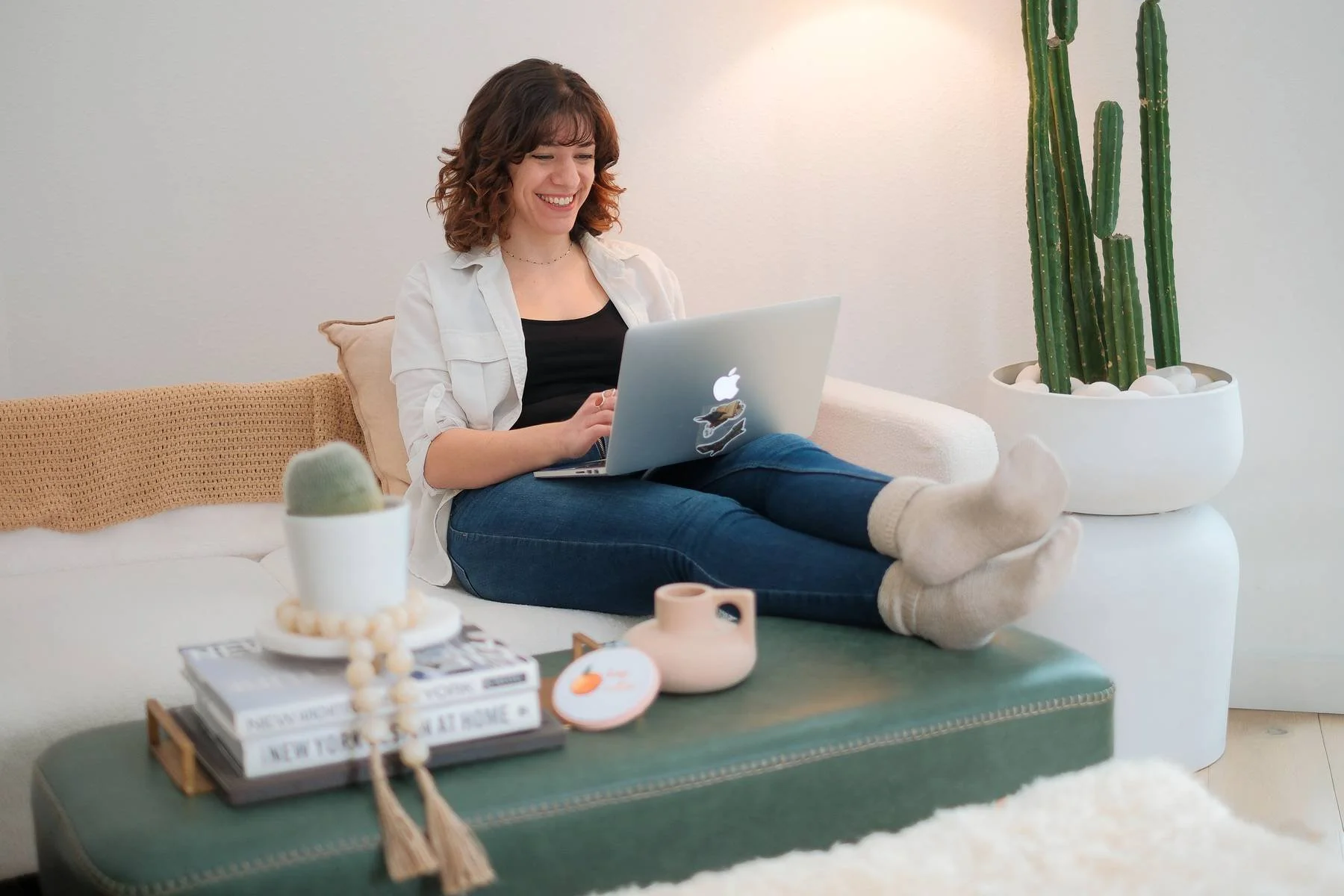 Website Copywriter Rebecca sitting on a couch with her legs up while typing on a laptop.