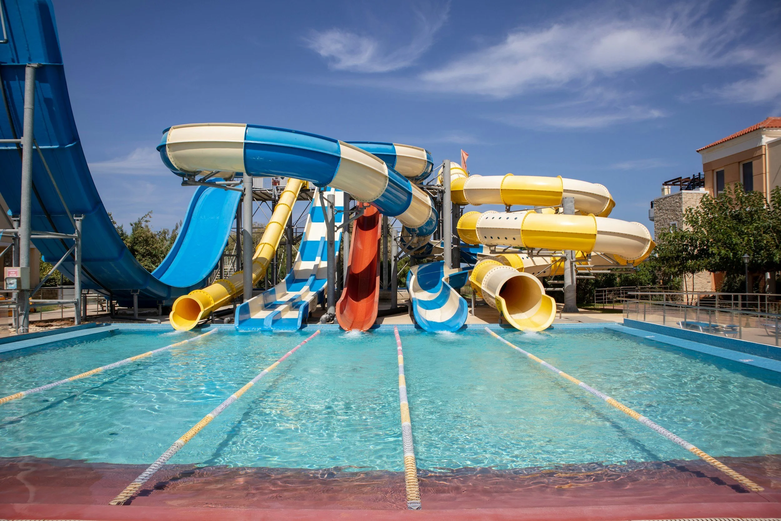 Waterpark with multiple colorful slides over a pool under a blue sky.