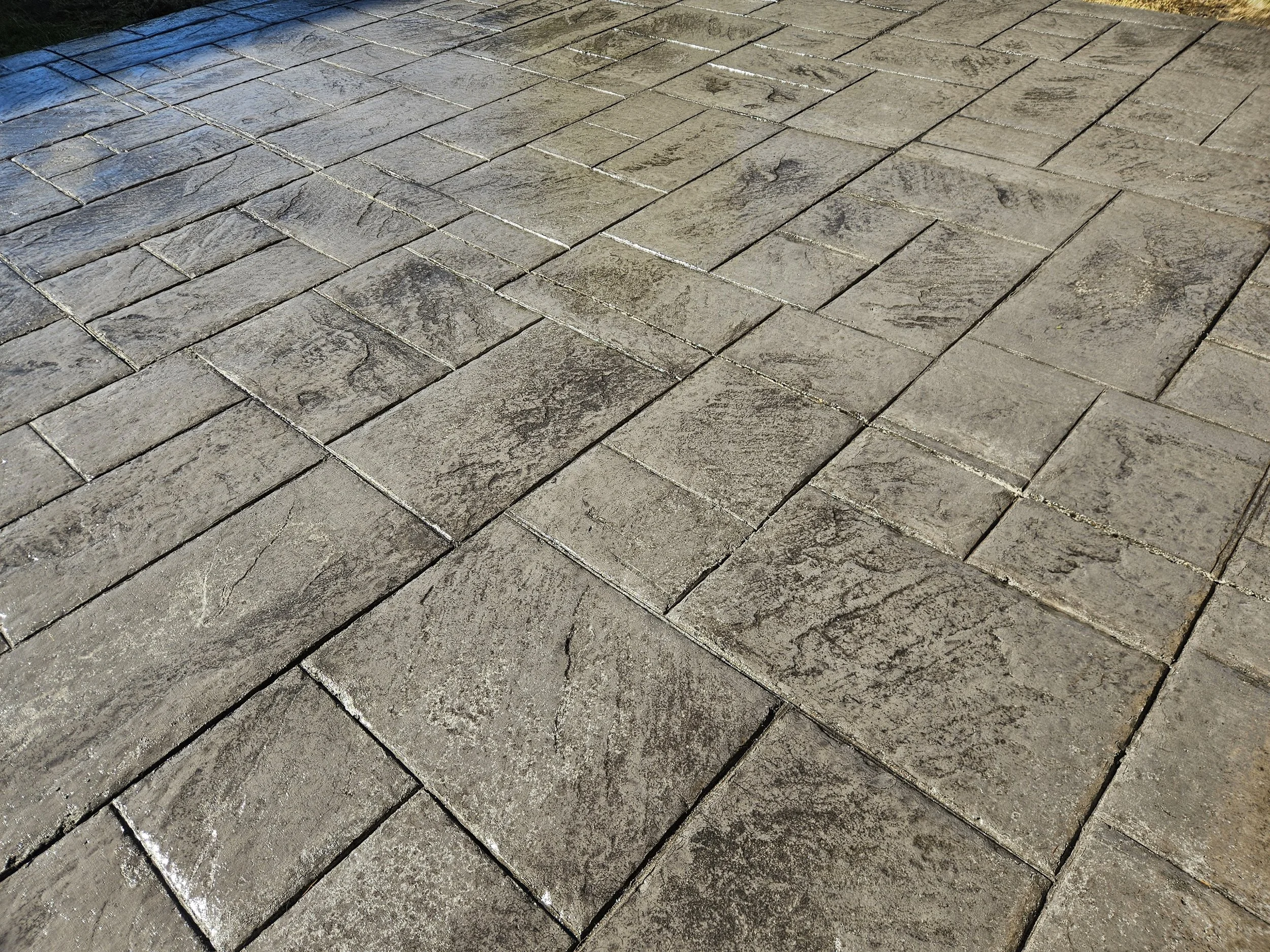 Concrete paver driveway with textured rectangular stones arranged in a staggered pattern.