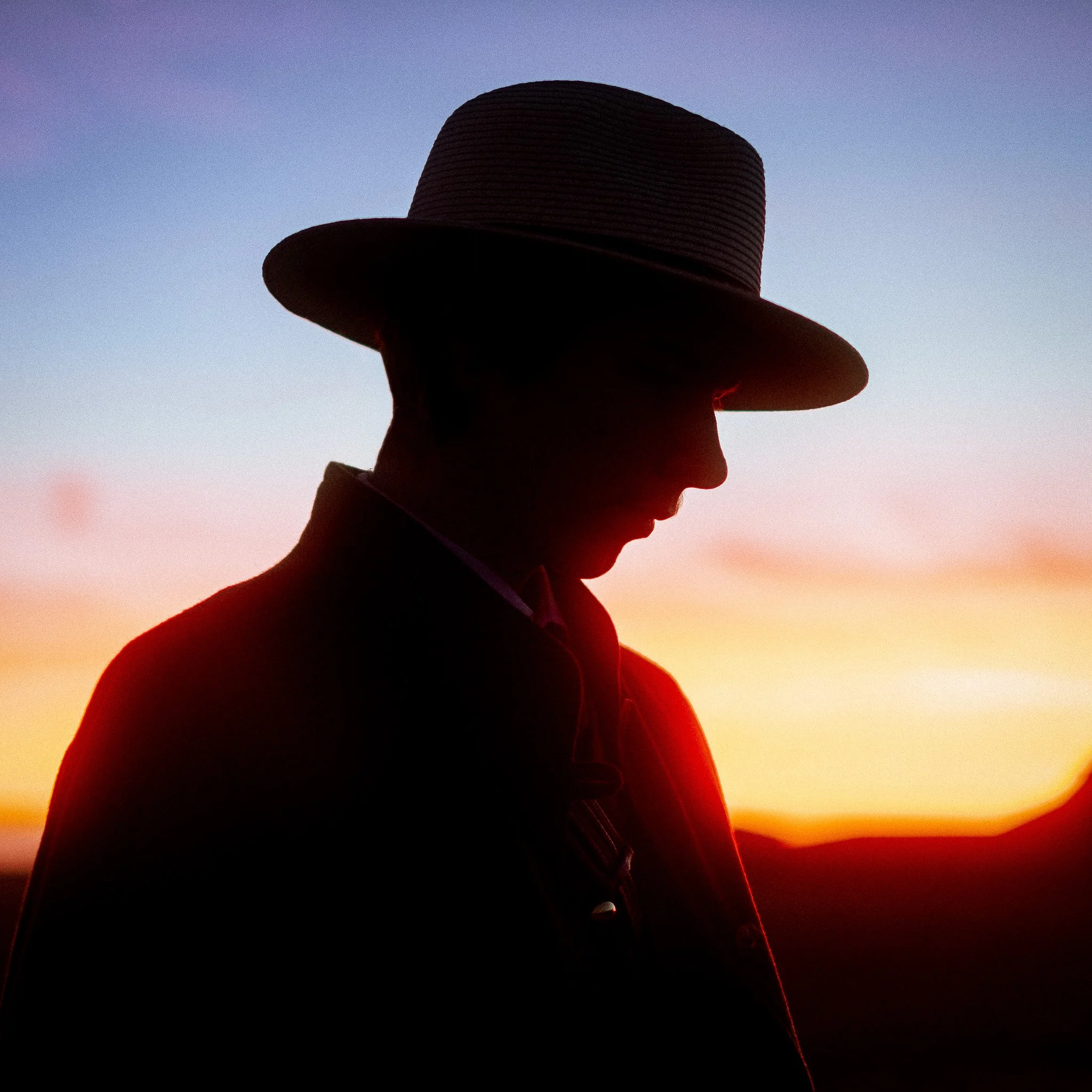 Silhouette d'une personne portant un chapeau, vue de profil, lors d'un coucher de soleil.