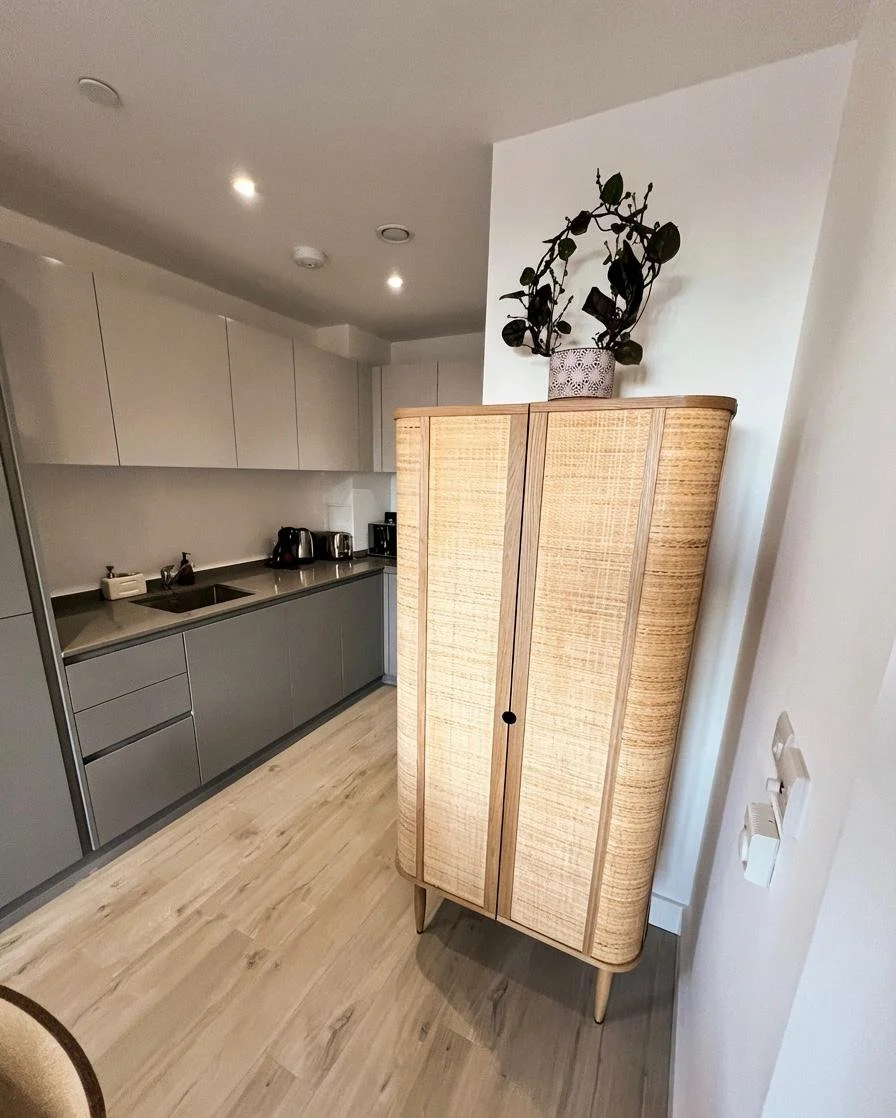 Grey kitchen with rattan storage cabinet and sculptural accessory, Battersea London interior design by Rodolfo Falcao