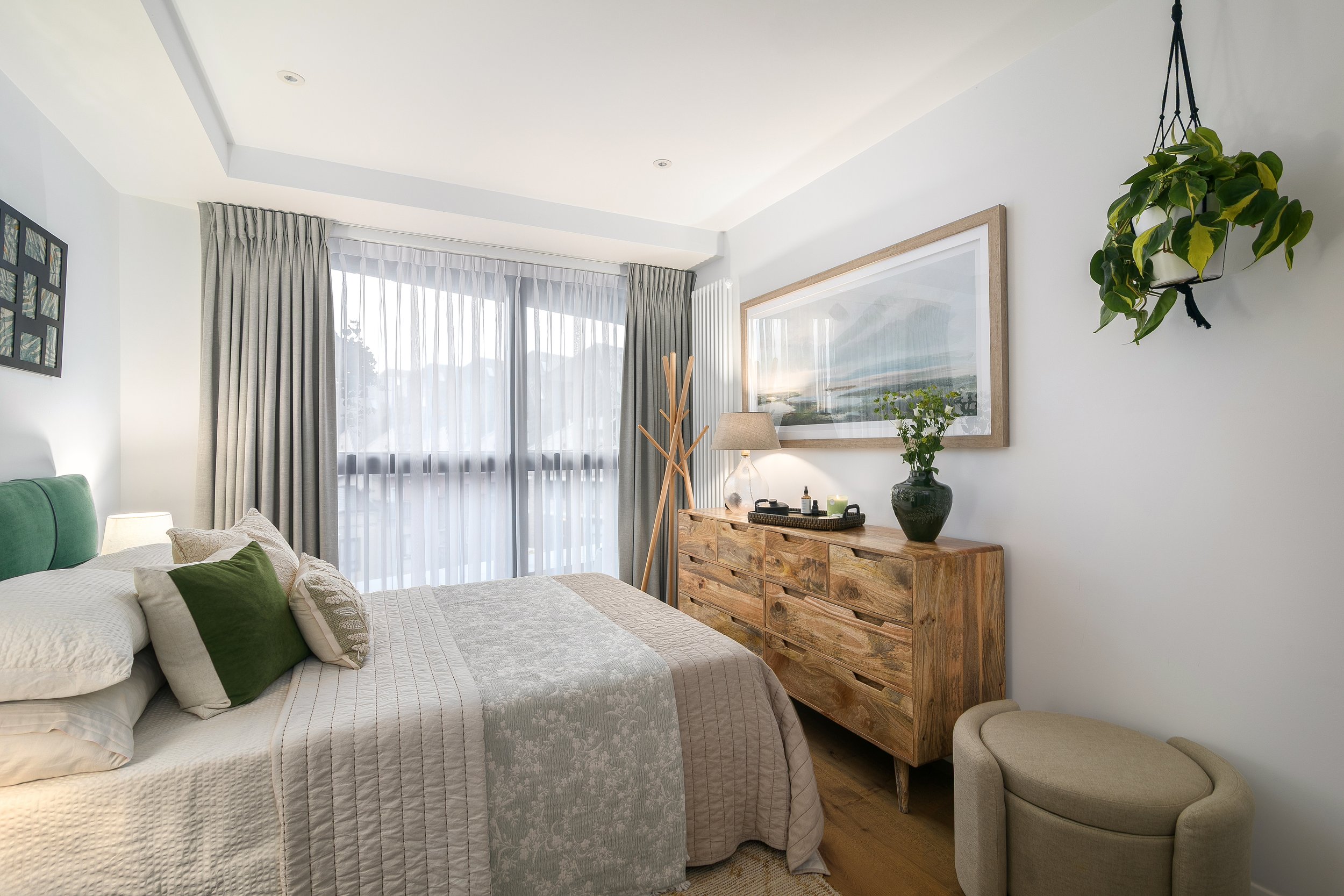 Calm neutral bedroom with rattan chest of drawers and landscape artwork, Limehouse Cut London apartment by Rodolfo Falcao