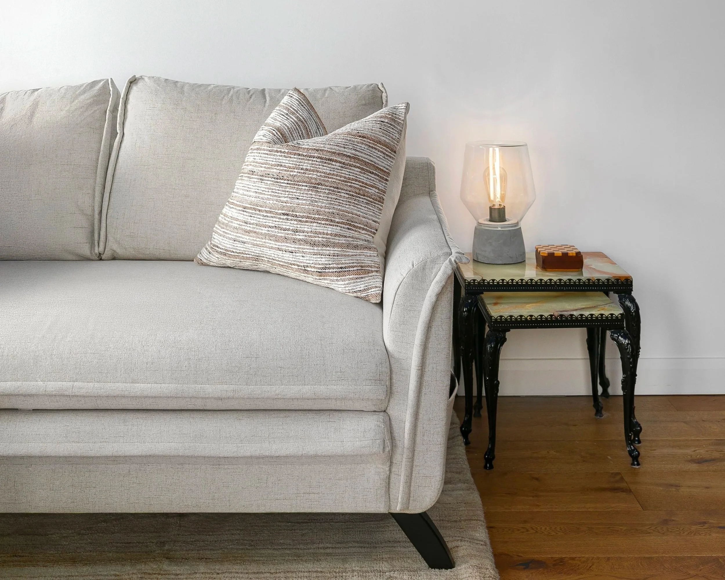 Neutral linen sofa with textured cushions and side table, Bow East London apartment by Rodolfo Falcao