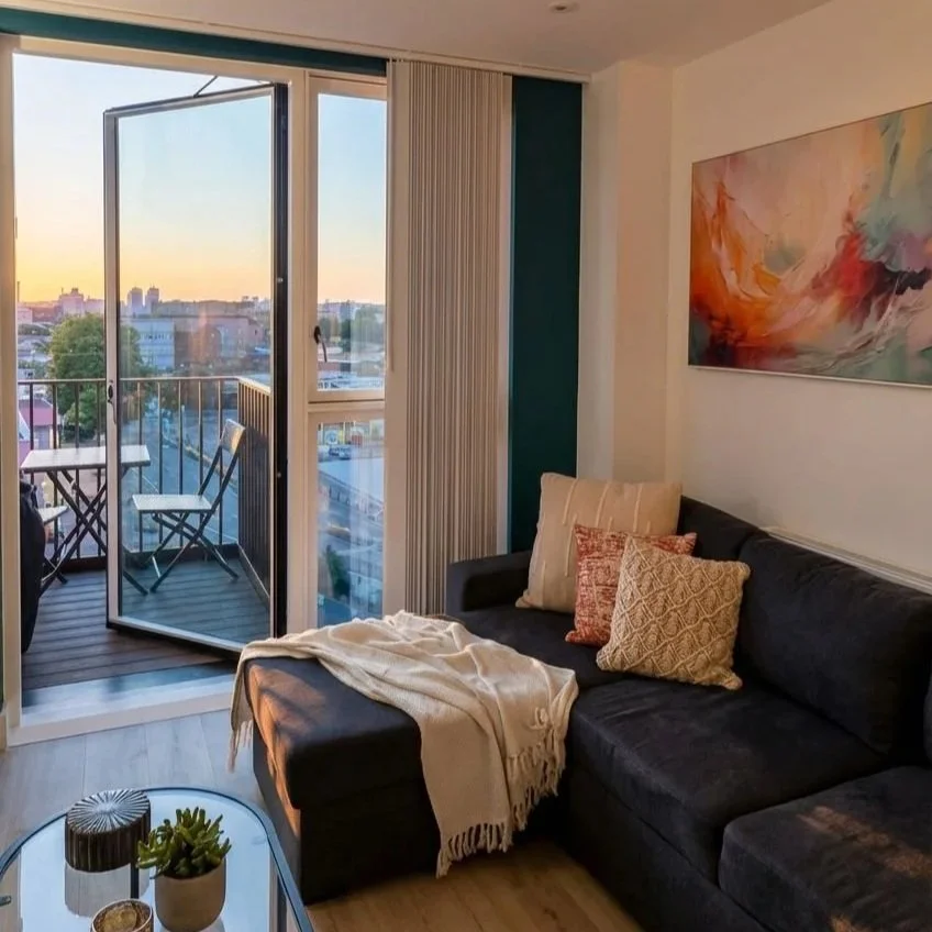 Living room with city views at sunset and colourful abstract artwork, Battersea London flat by Rodolfo Falcao