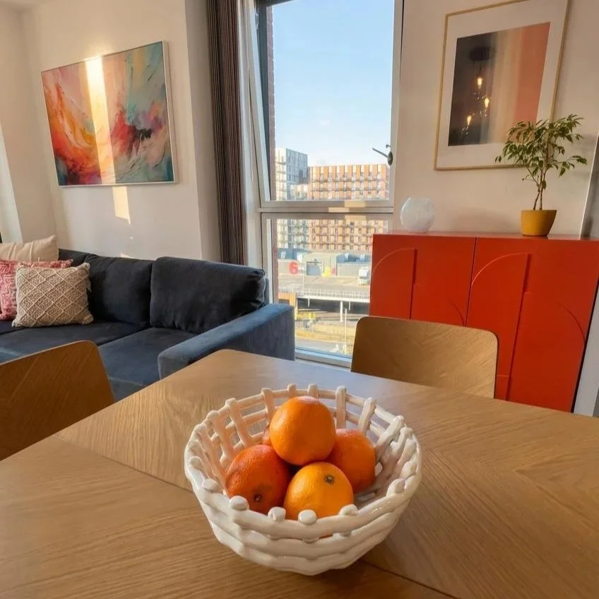 Open plan dining and living area with city views and orange accents, Battersea London flat by Rodolfo Falcao