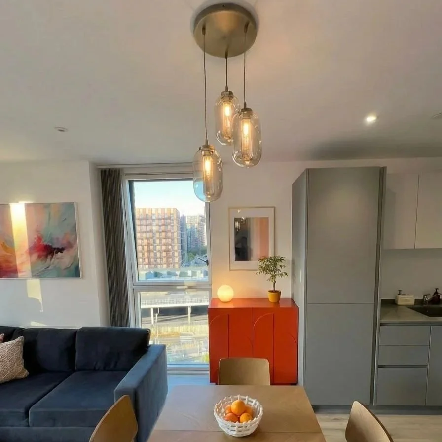 Living room with gold pendant lights and forest green cabinetry, Battersea London flat by Rodolfo Falcao