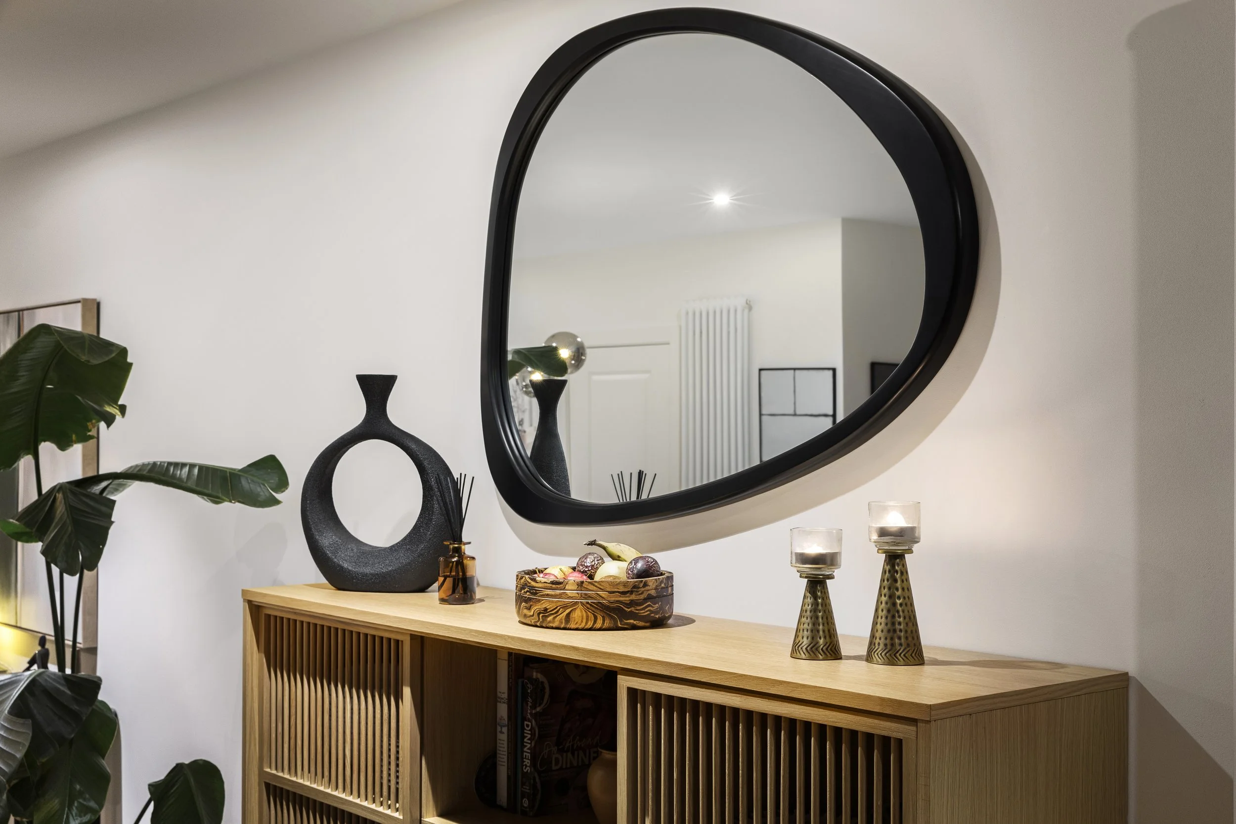 Organic shaped mirror above ribbed sideboard with ceramic accessories, Limehouse Cut London by Rodolfo Falcao