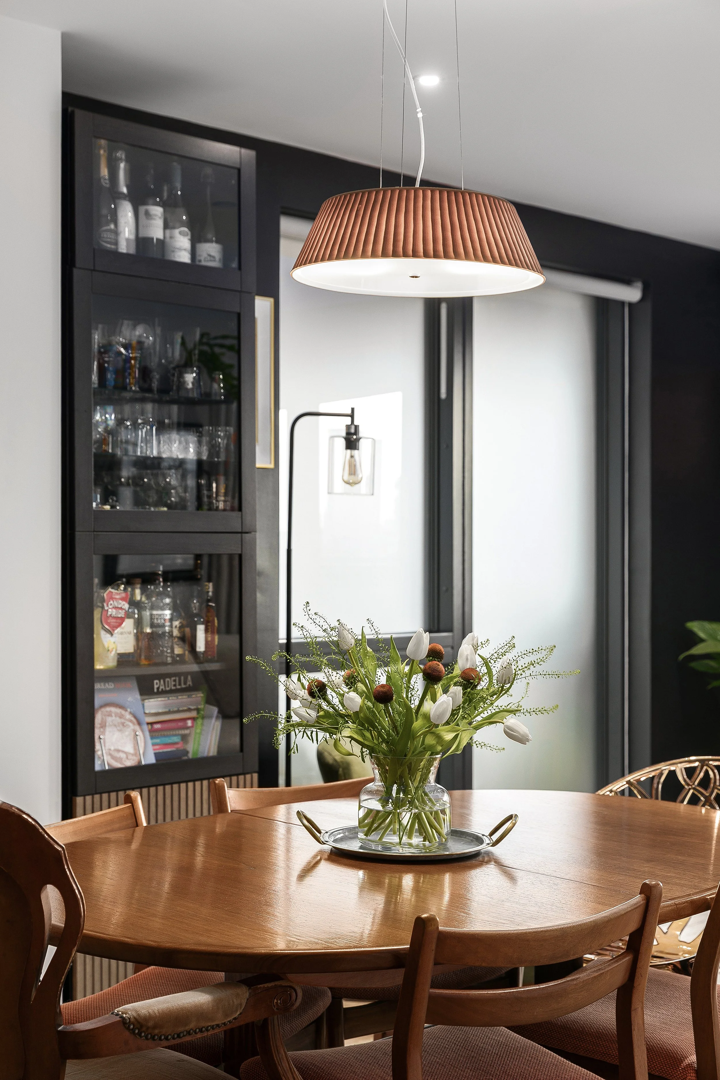Dining area with black drinks cabinet and woven pendant light, Bow East London apartment by Rodolfo Falcao