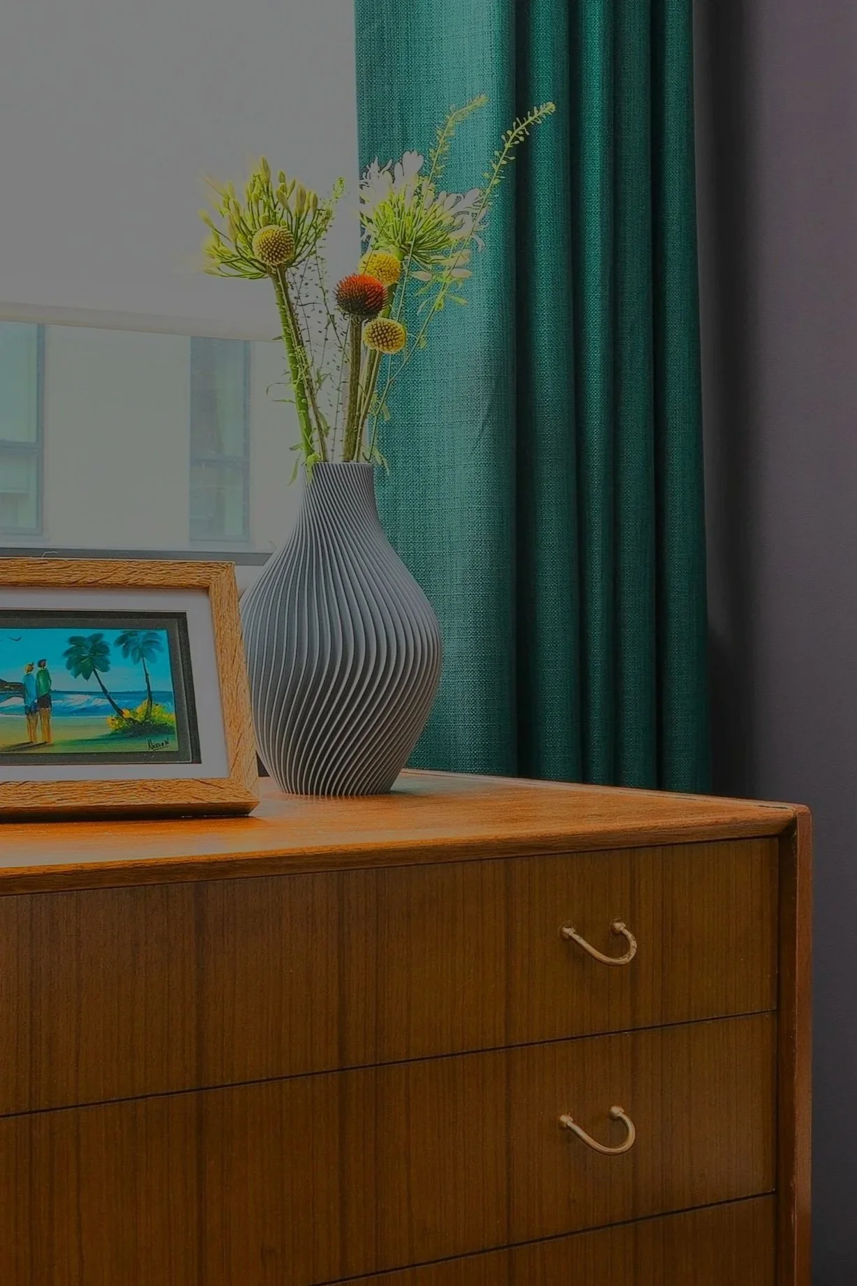 Eclectic interior styling by Rodolfo Falcao, vintage wooden dresser with floral arrangement and coastal artwork, London interior design