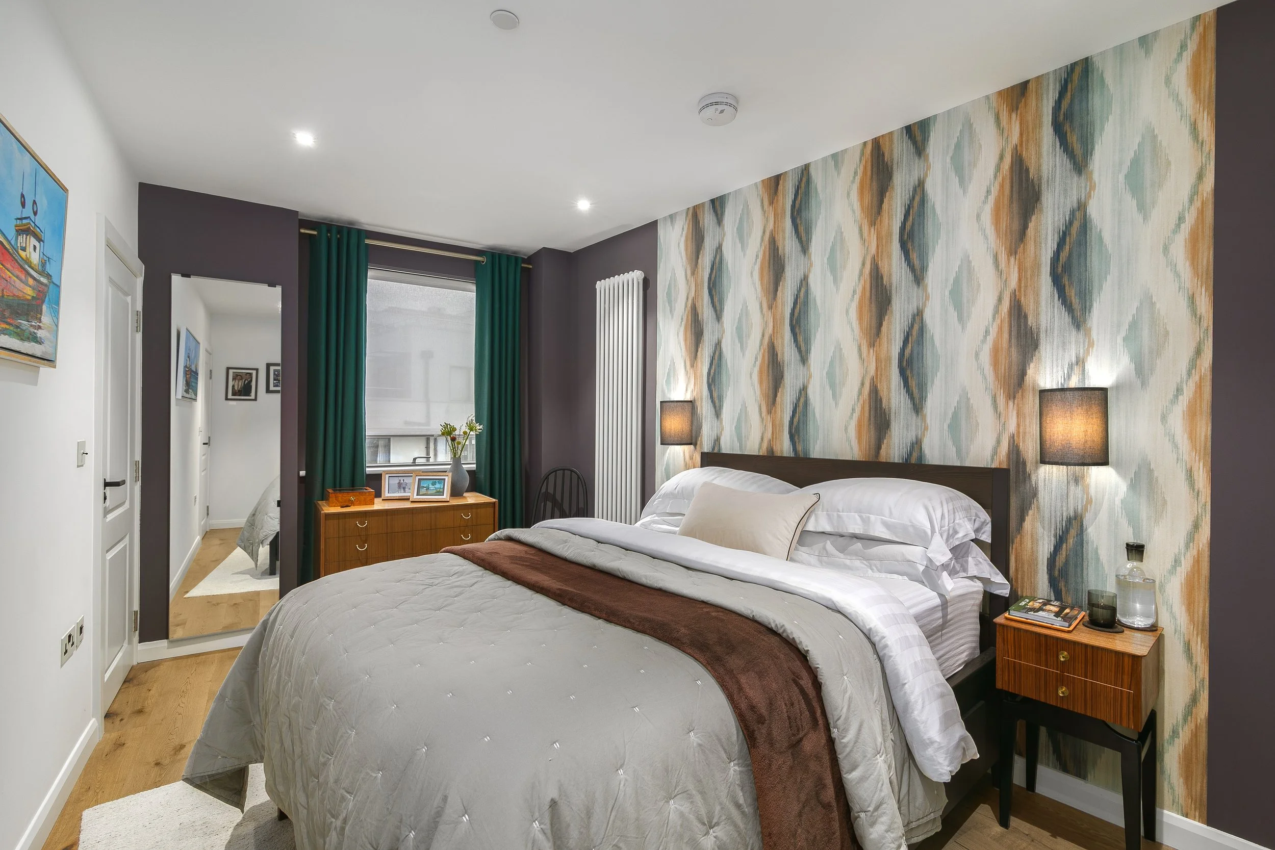 Primary bedroom with aubergine walls, ikat-print feature wall and teal curtains, Bow East London apartment by Rodolfo Falcao