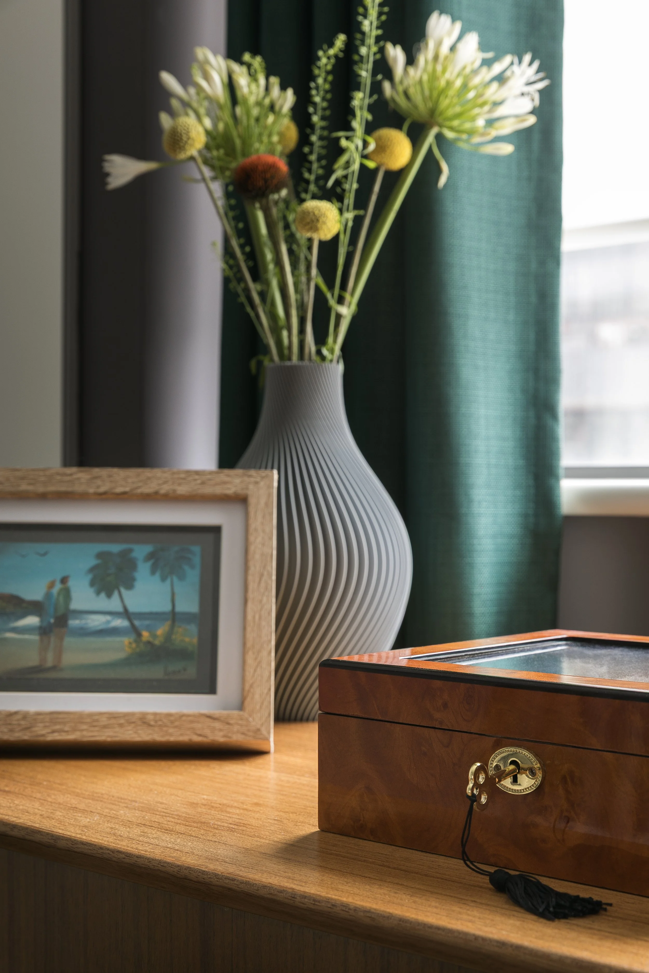 Styled surface detail with ribbed vase, coastal artwork and teal curtains, Bow East London apartment by Rodolfo Falcao