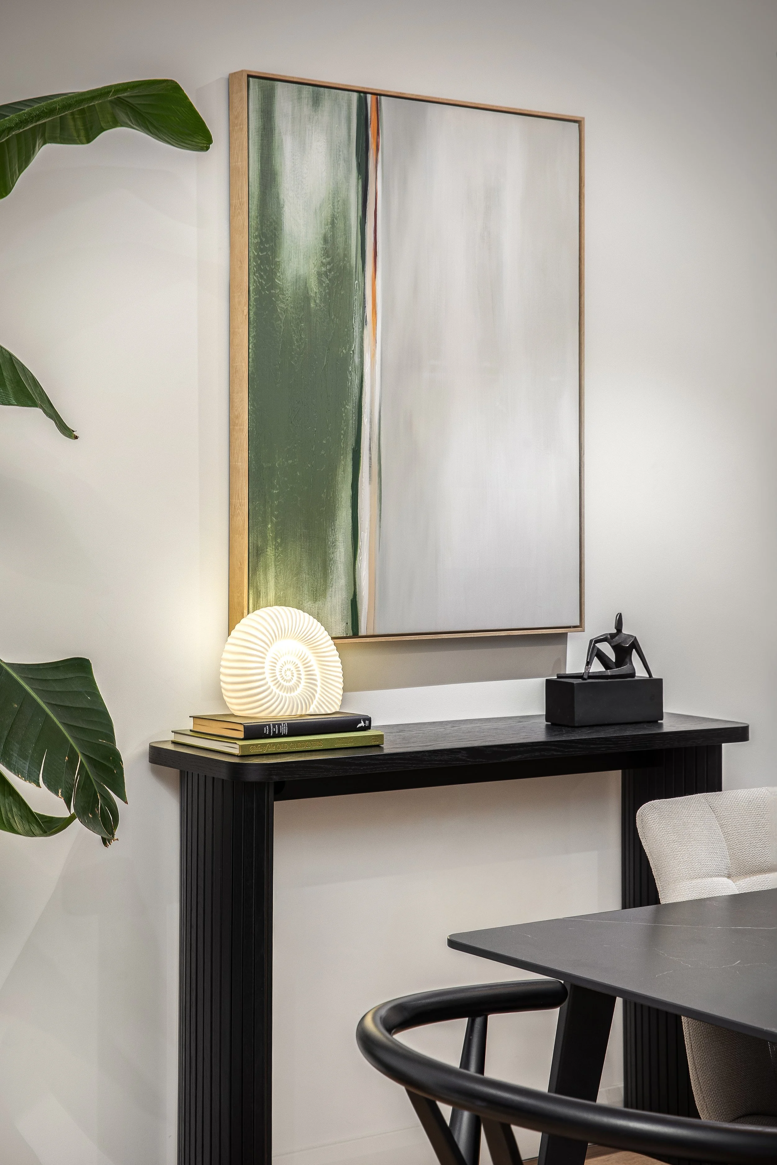 Black console table with gold framed mirror and globe lamp, Limehouse Cut London apartment by Rodolfo Falcao