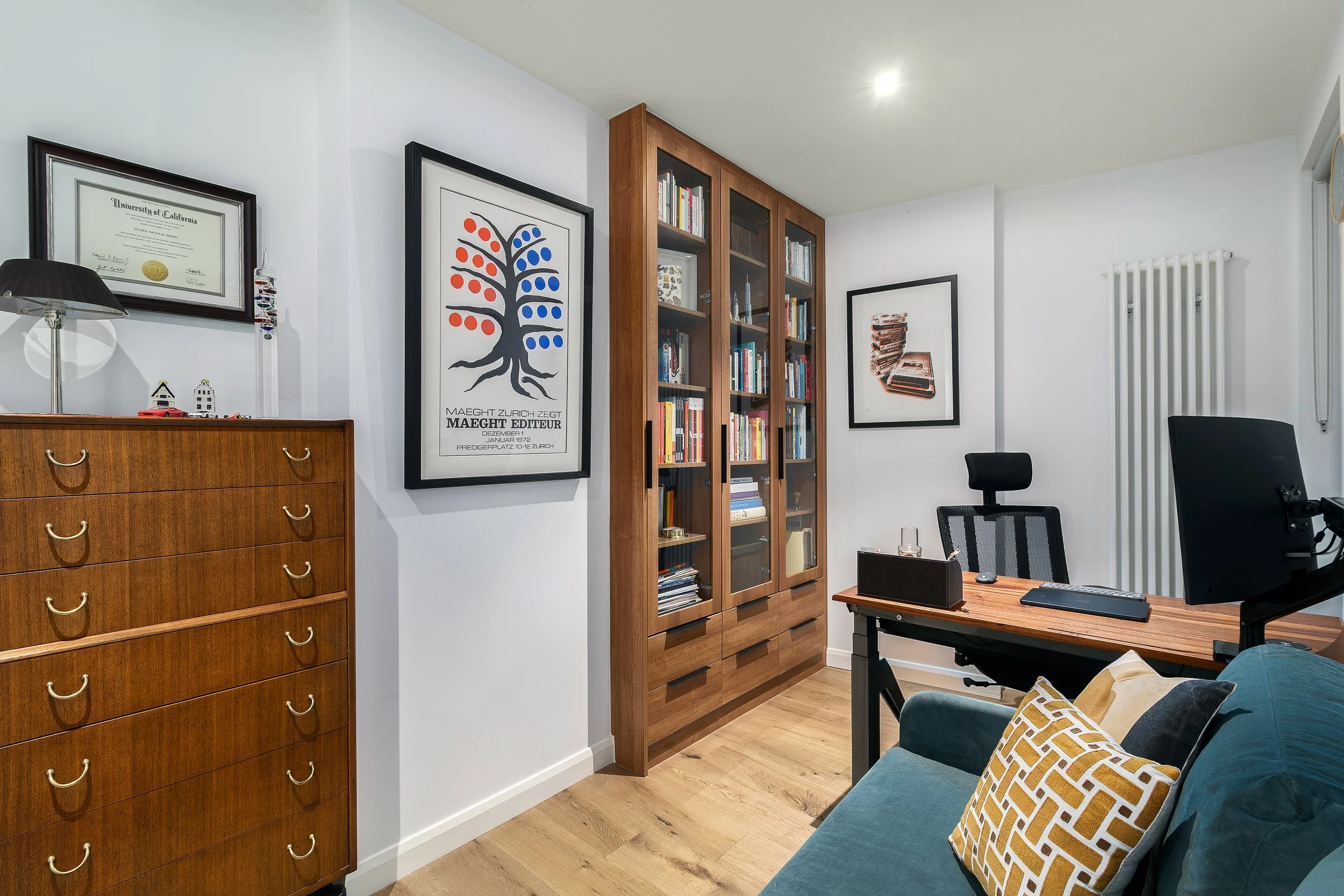 Home office with glazed wooden bookcases and exhibition poster artwork, Bow East London apartment by Rodolfo Falcao