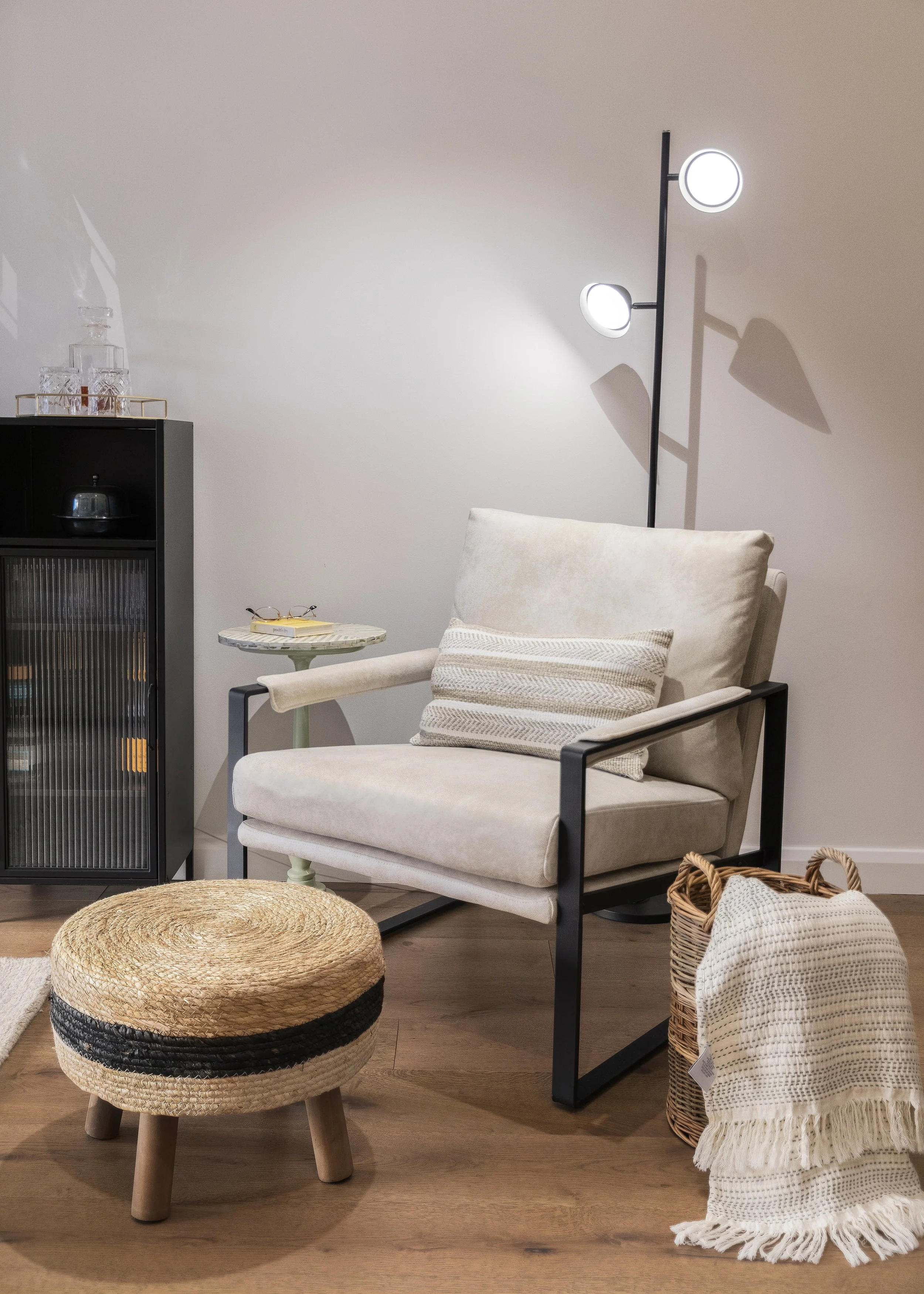 Neutral armchair with woven footstool and black side table, Limehouse Cut London apartment by Rodolfo Falcao