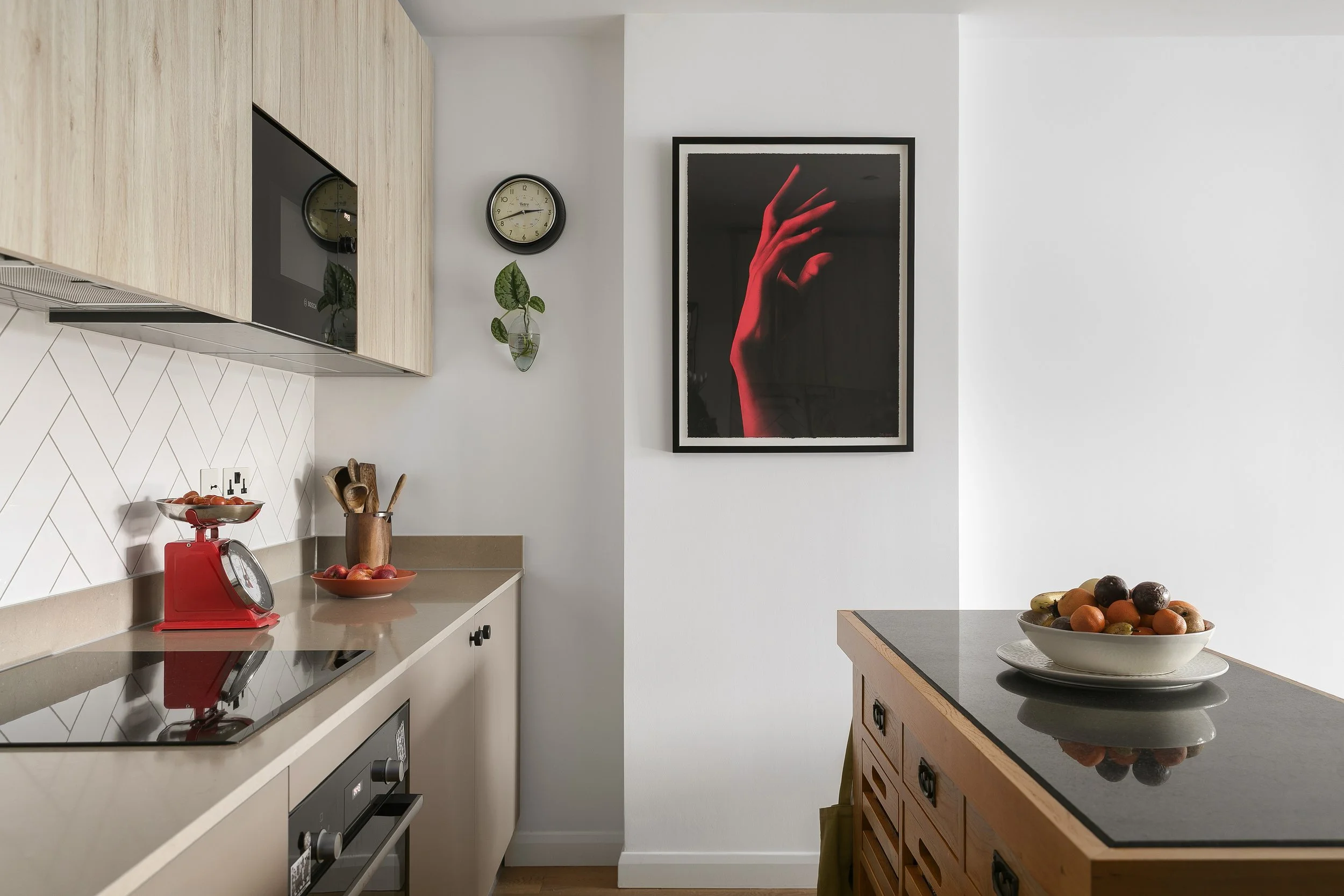 Clean white kitchen with bold neon pink artwork, Bow East London apartment by Rodolfo Falcao
