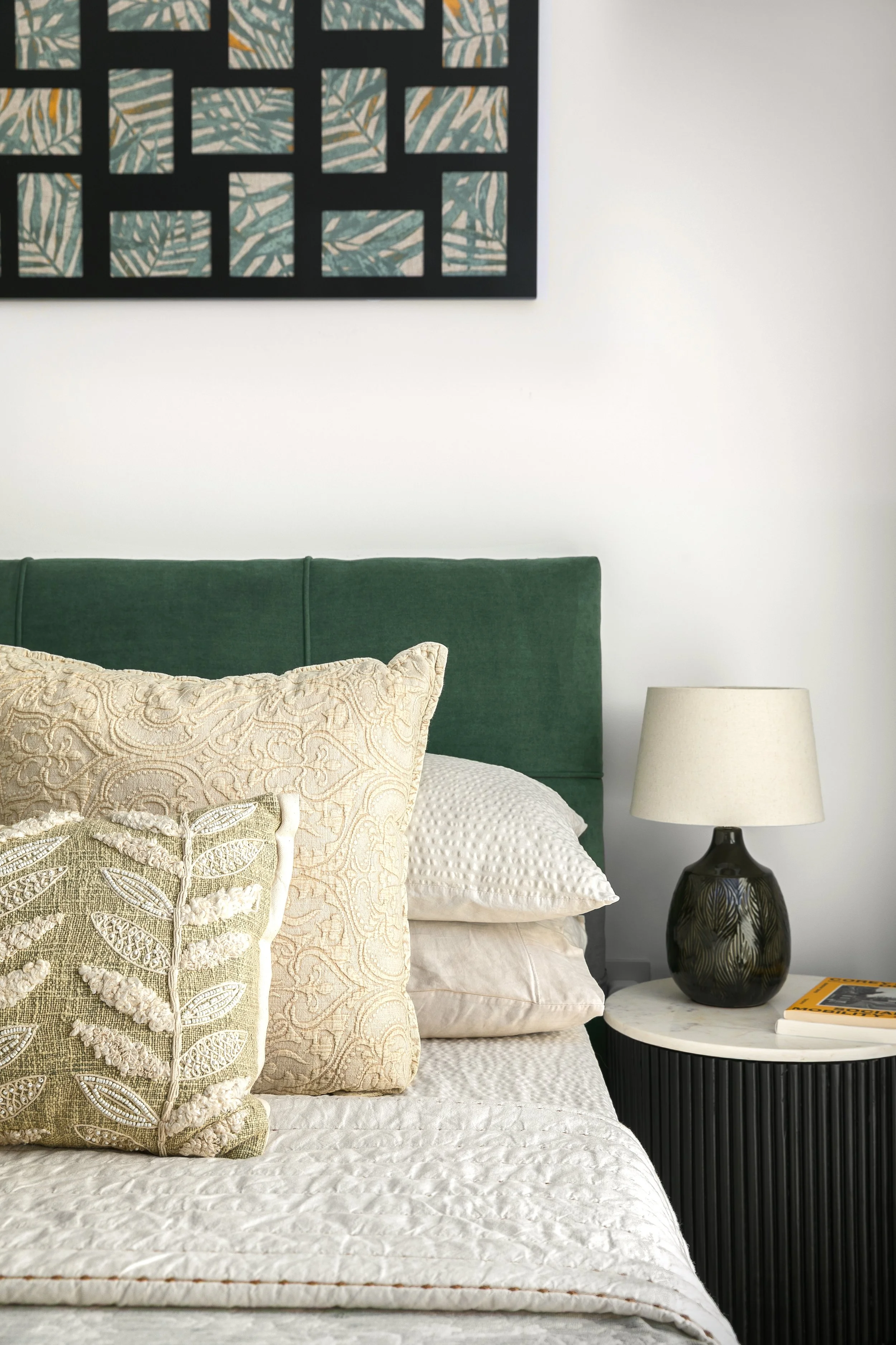 Bedroom with deep green velvet headboard and layered neutral cushions, Limehouse Cut East London by Rodolfo Falcao
