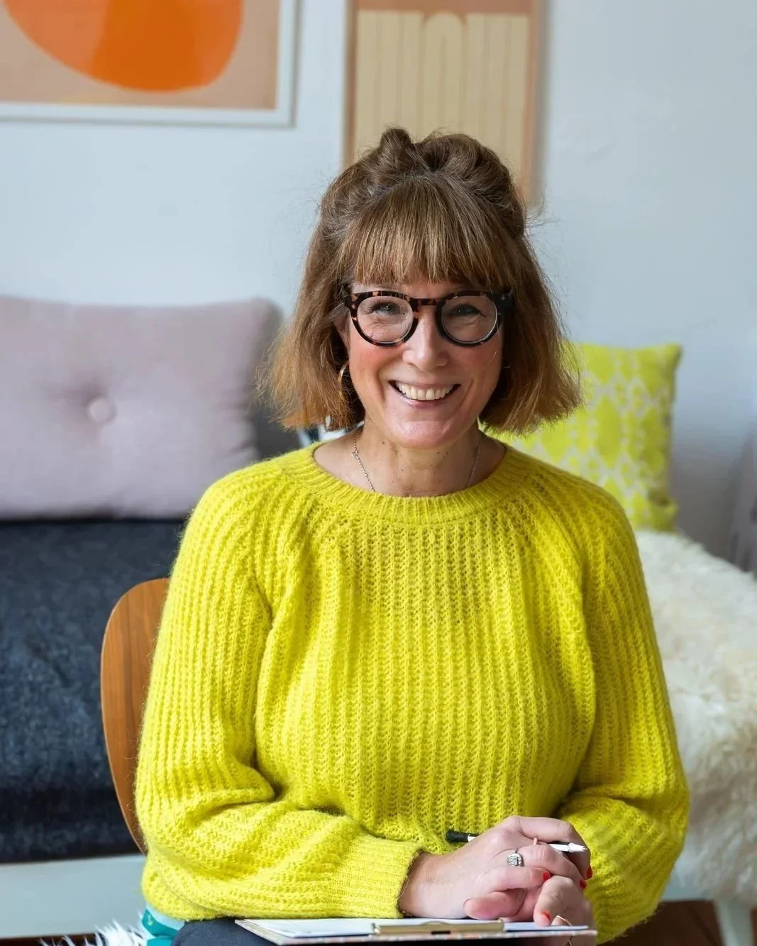 Porträt von Fabienne Schröder-Rust, Heilpraktikerin für Psychotherapie, freundlich lächelnd im gelben Pullover auf einem Sessel in ihrer Praxis in Frankfurt am Main