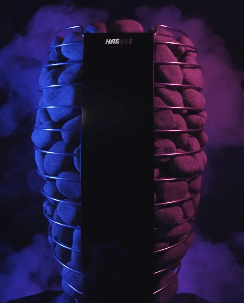 A cylindrical wire rack filled with rocks, illuminated with purple and blue lighting, with mist or smoke in the background.