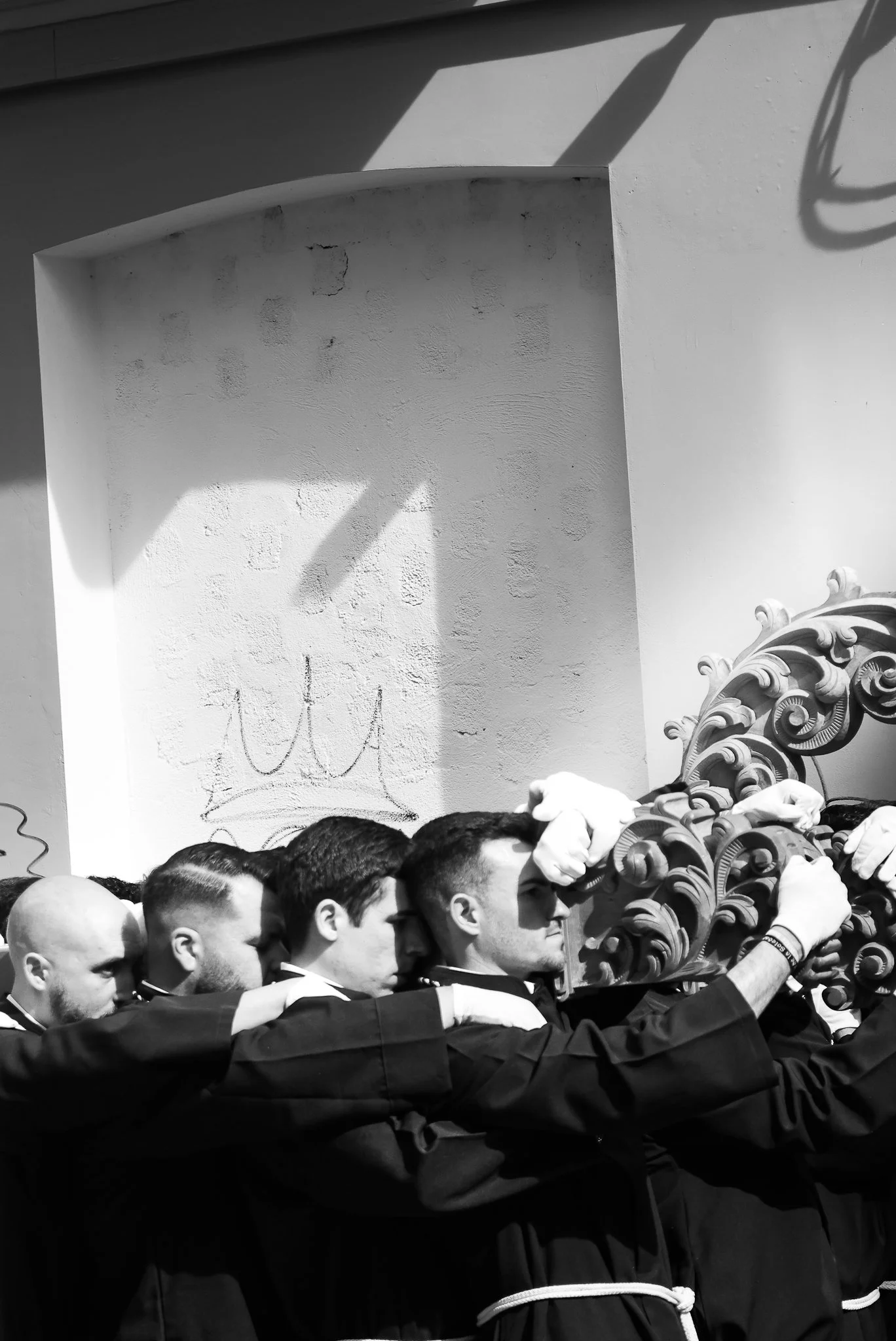A group of men dressed in religious clothing and white gloves carrying the 'body of christ' through the city centre of Mallorca during Easter Week, Spain. Black and White.