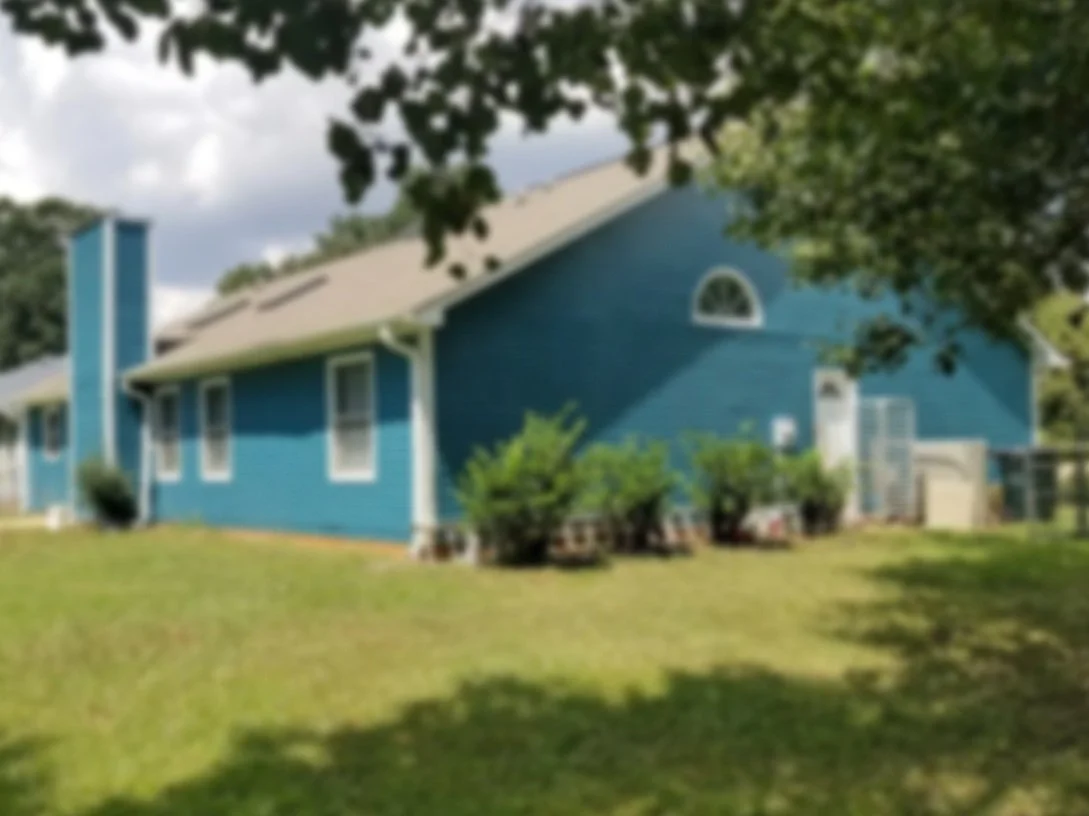 Blurred image of a seafoam blue house with white trim paint, in Simpsonville, SC.