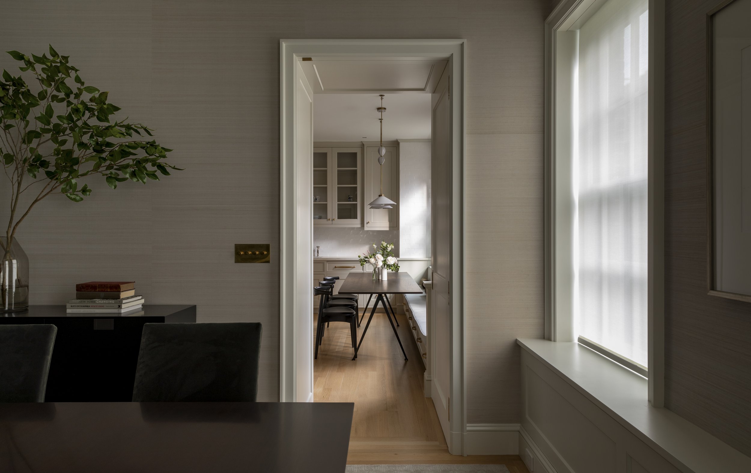 View of a dining area and kitchen through an open doorway in a well-lit, modern home interior.