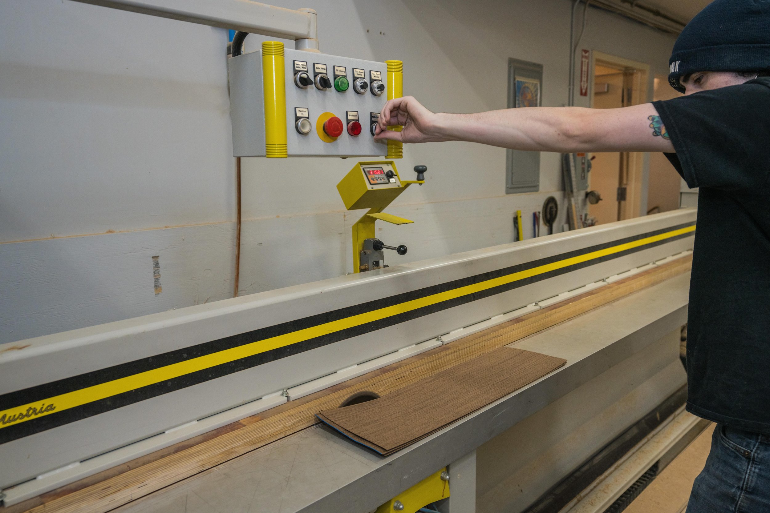 Person operating a woodworking edge banding machine in a workshop.