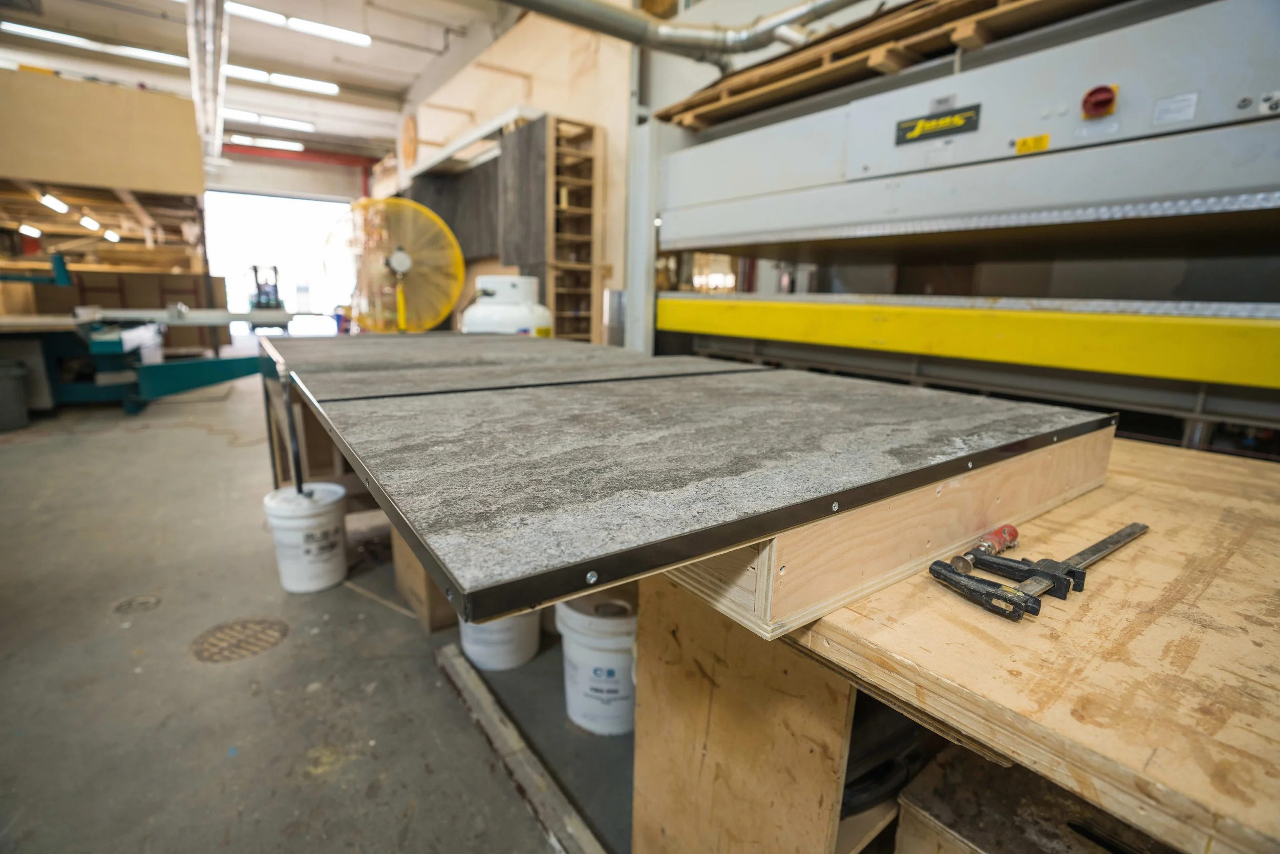 Workshop with workbench under construction, tools, wood, and supplies arranged in a woodworking shop.
