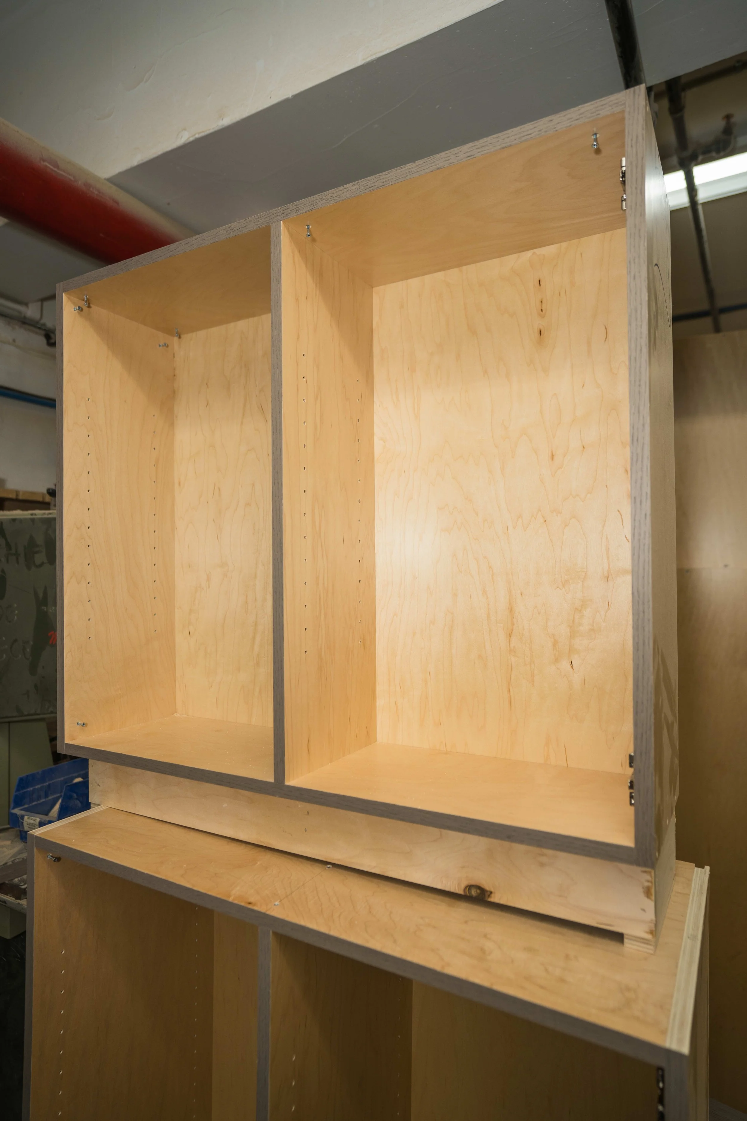 Unfinished wooden shelving unit with three compartments, mounted on a wall, with visible screws and hardware.