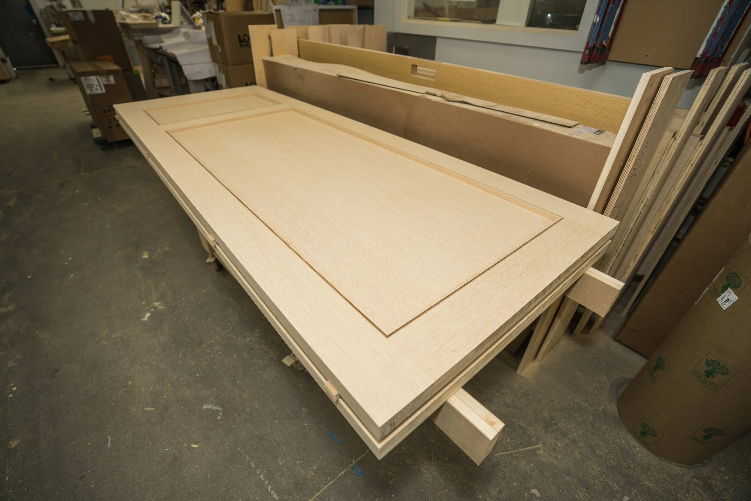 Unassembled wooden cabinet doors on a worktable in a woodworking shop.