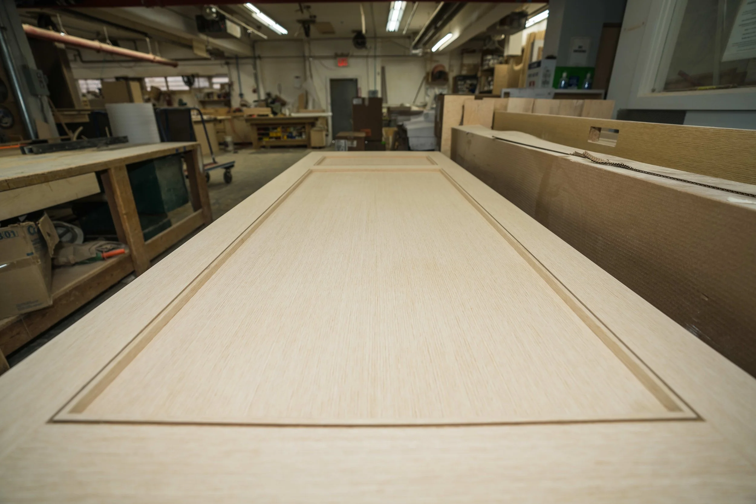 Wooden door with inset panel lying flat on workbench in woodworking shop.