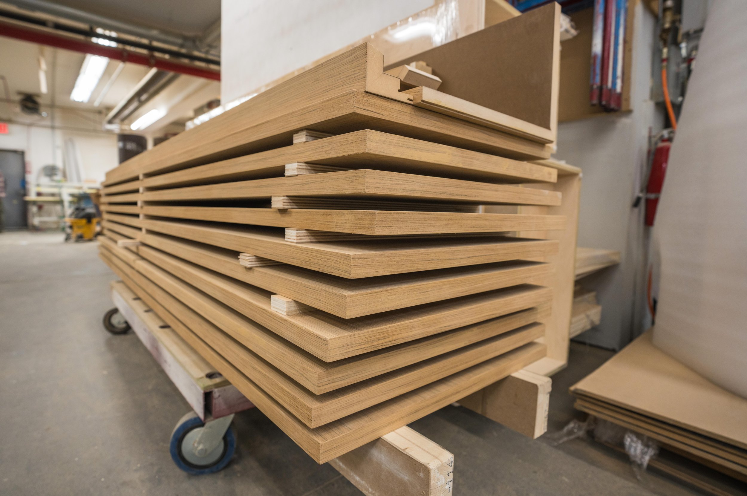 Stacked wooden slats on a cart in a woodworking shop